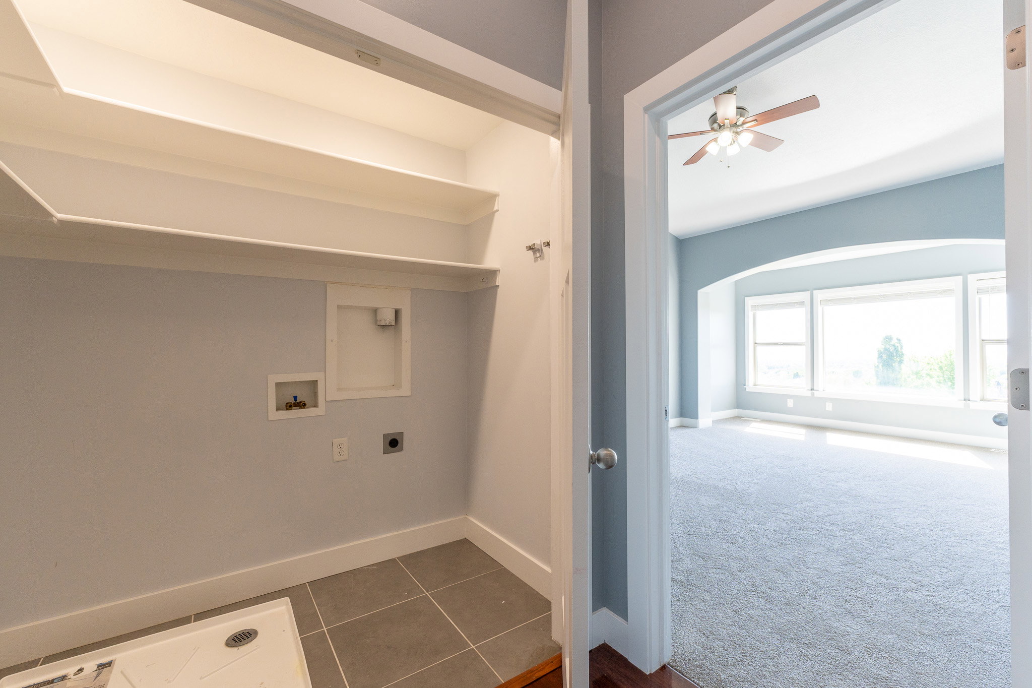 Dedicated laundry area with built-in shelving and tile flooring