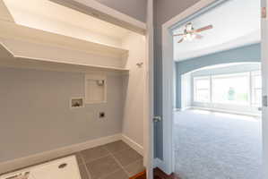 Dedicated laundry area with built-in shelving and tile flooring