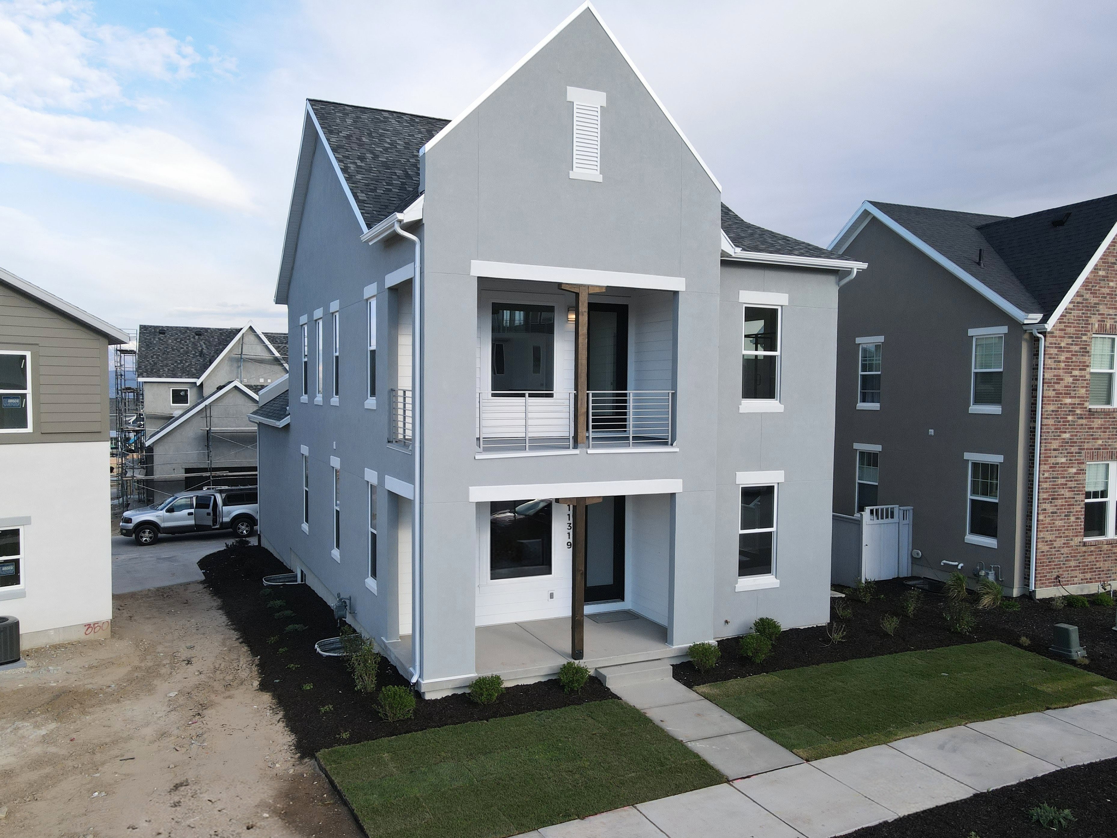 Modern farmhouse exterior with light gray stucco finish and a dark shingled roof