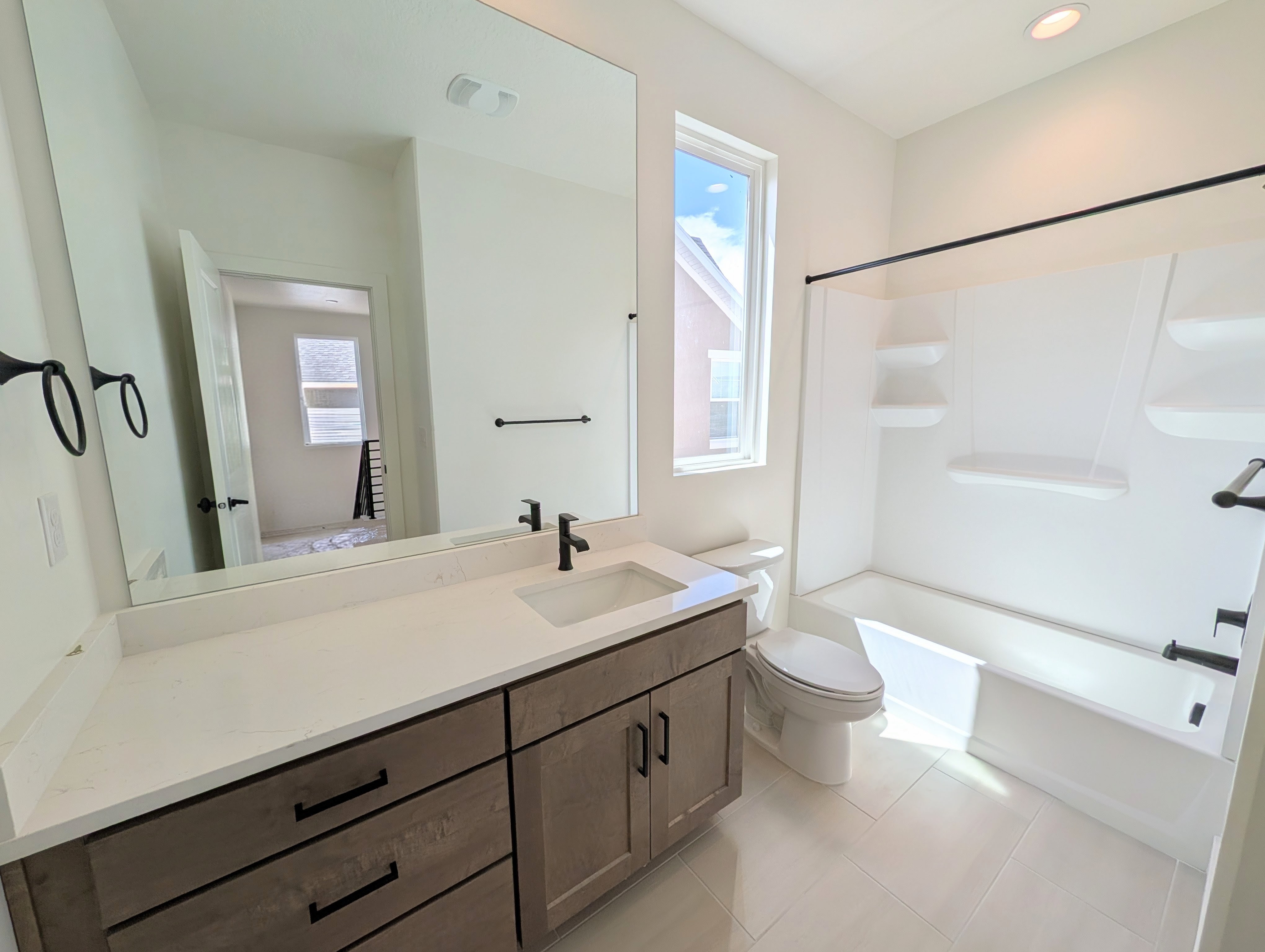 Bathroom featuring a single vanity with stone-finish countertop, undermount sink, and wood-finish cabinetry