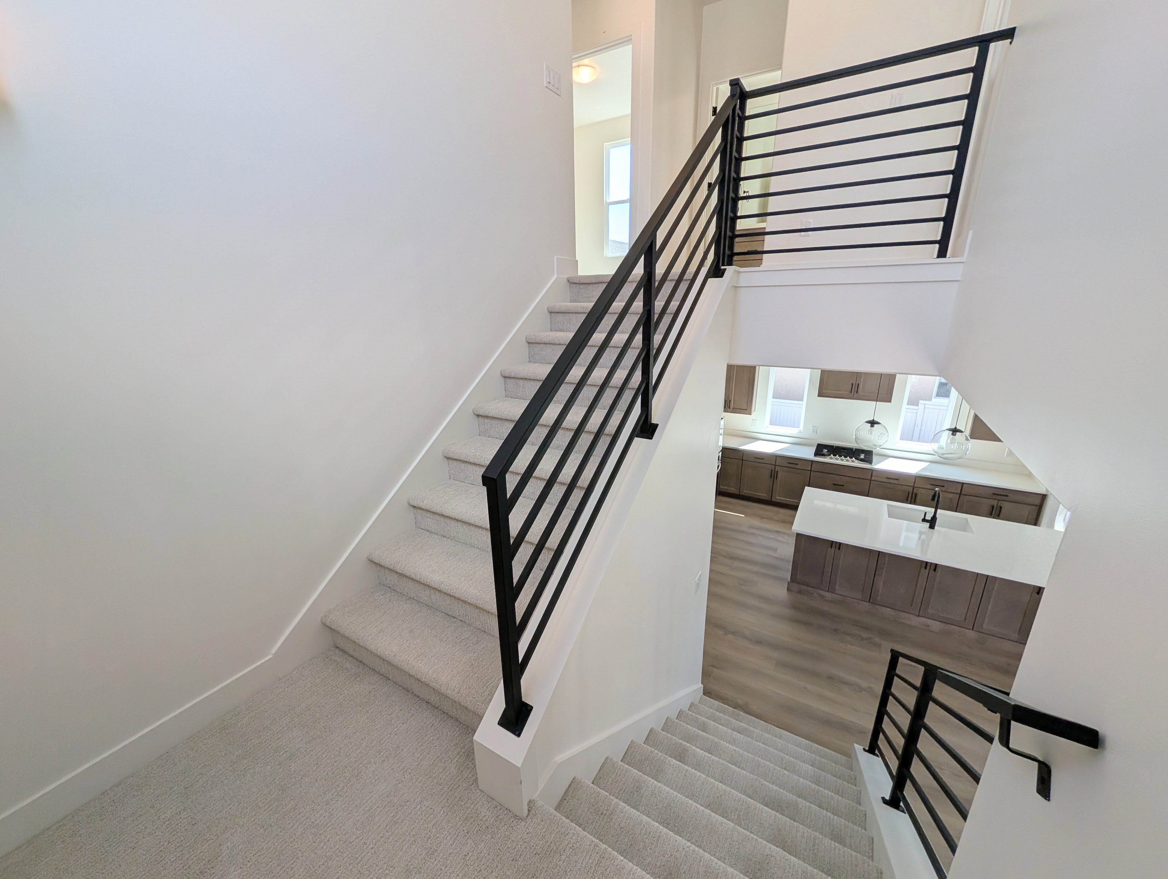Multi-level staircase featuring light-colored carpeting and modern horizontal metal railings