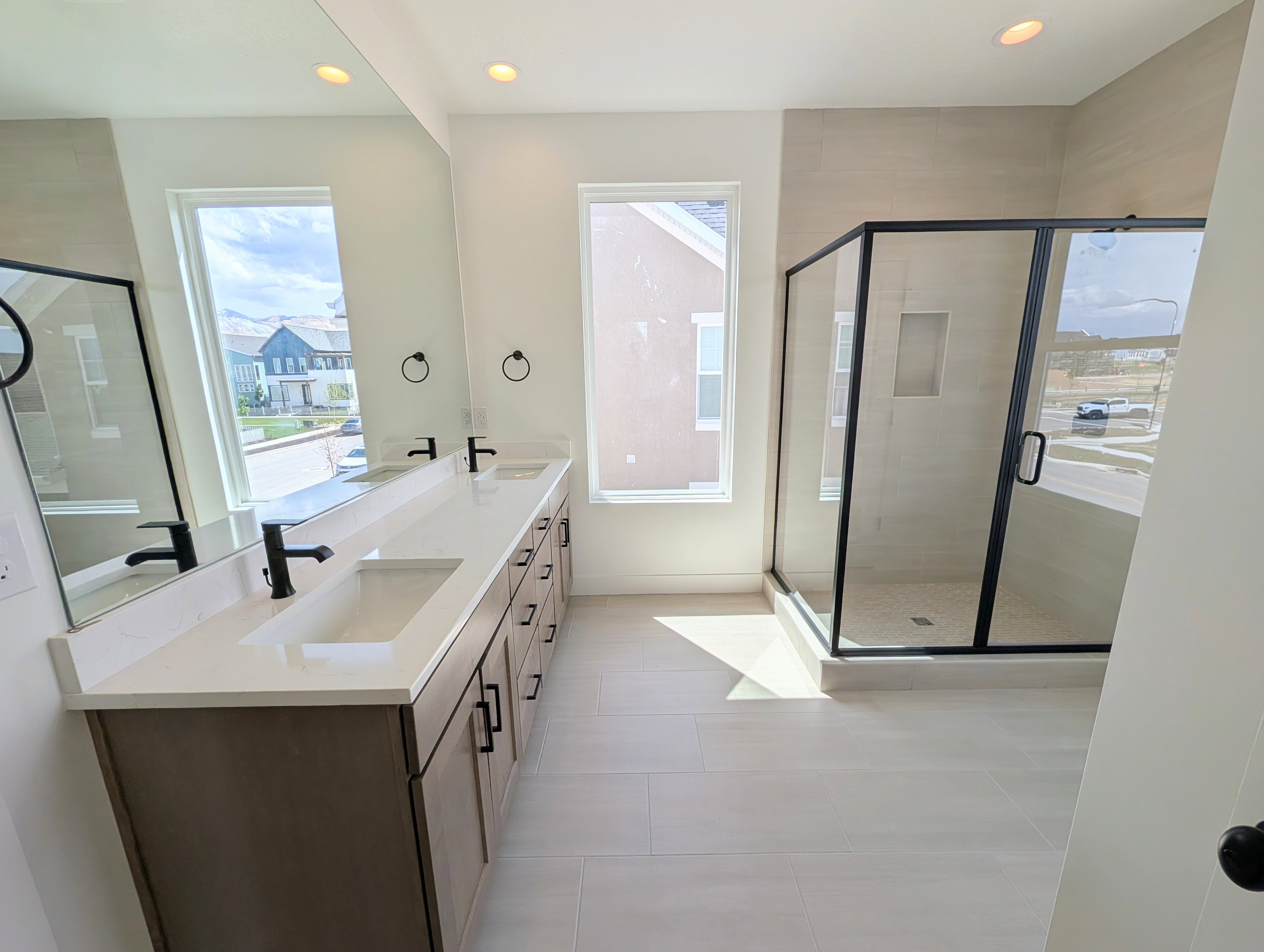 Primary bathroom with Dual vanity with integrated sinks, light-toned cabinetry, and matte black fixtures