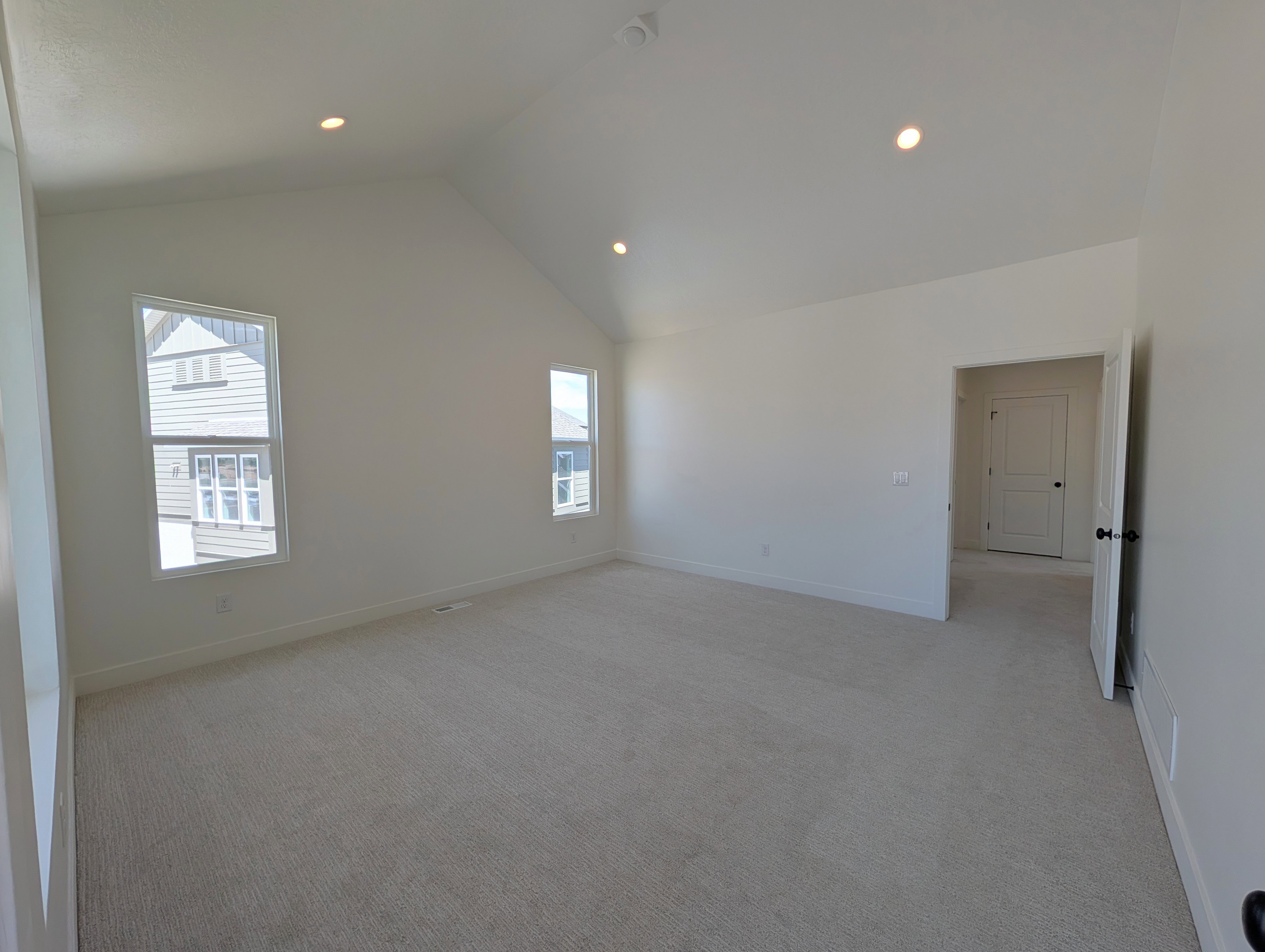 Primary bedroom featuring access to private balcony, vaulted ceilings, recessed lighting, neutral carpeting, and multiple windows