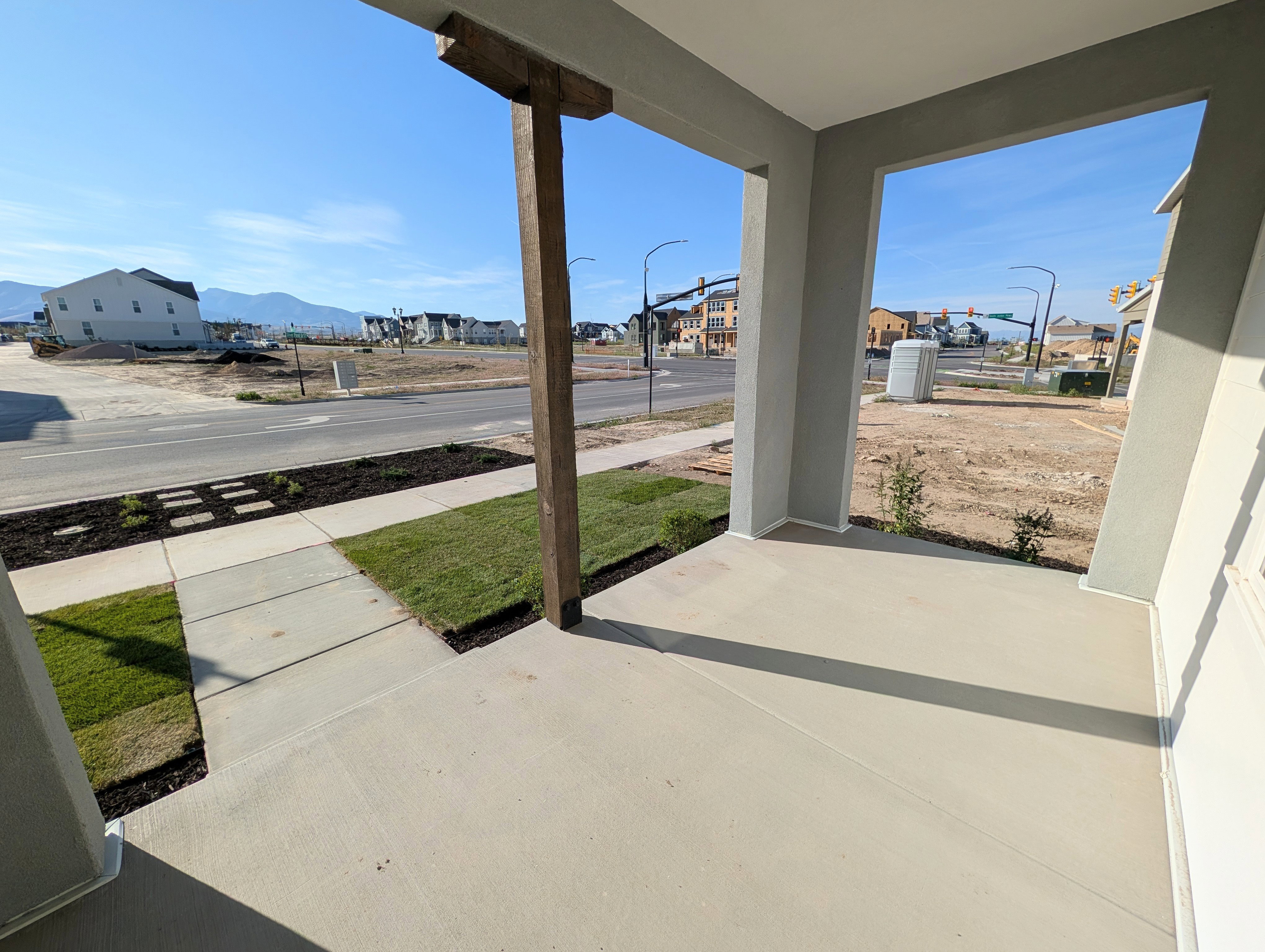 Spacious concrete front porch featuring a prominent wood beam detail