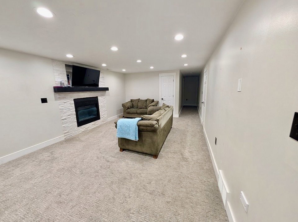 Media room featuring recessed lighting, plush carpeting, an electric fireplace with a stacked stone surround, and a dark wood mantel