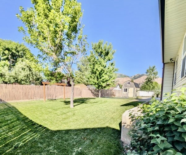 Expansive lawn featuring mature trees and a privacy fence