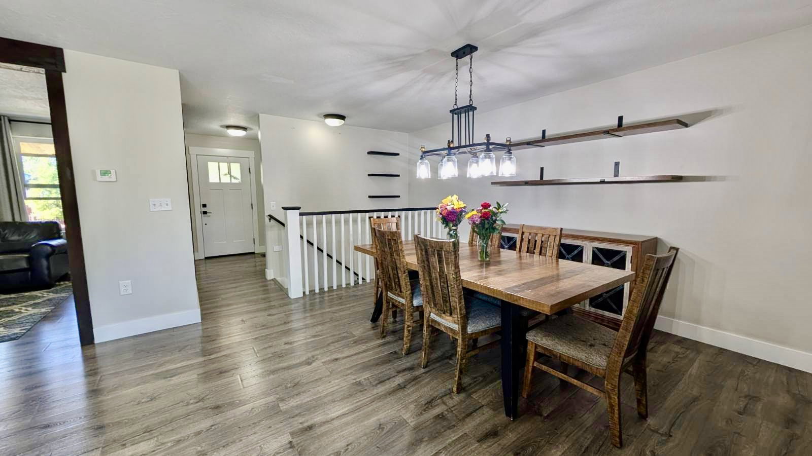 Open-concept dining area featuring wood-finish flooring, a contemporary chandelier, and built-in wall shelving