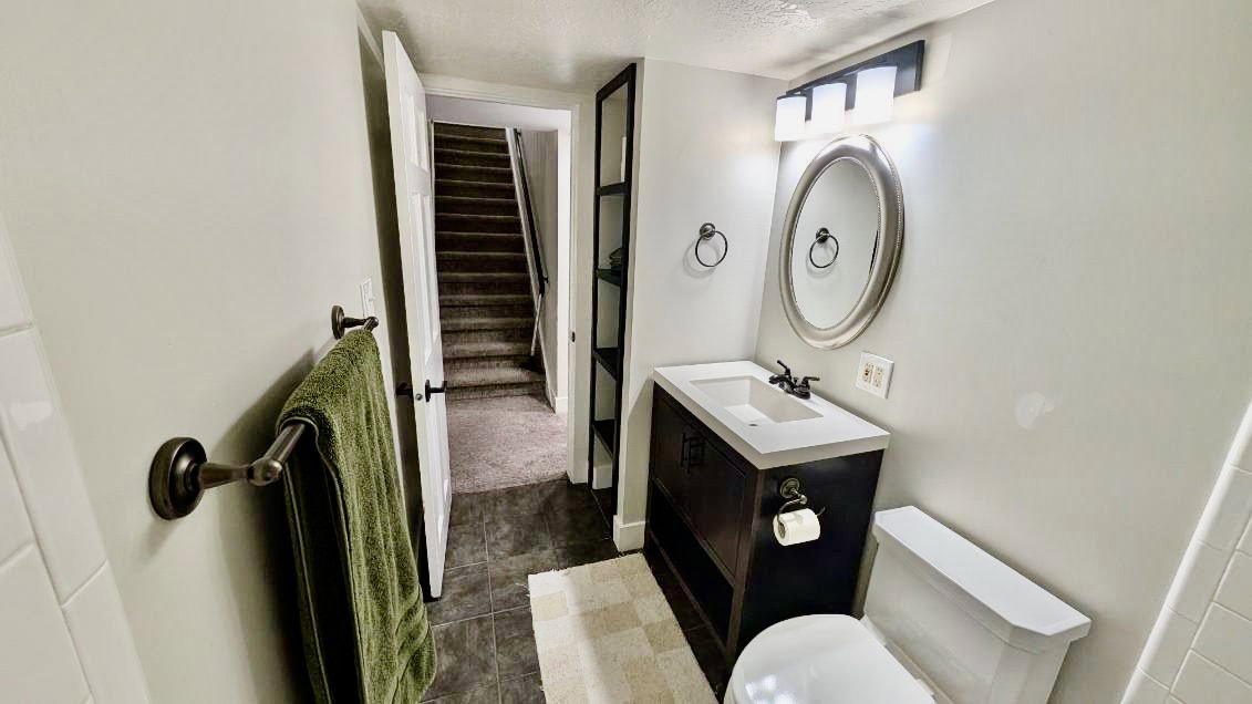 Bathroom featuring a dark wood-finish vanity with a white countertop and rectangular sink, an oval mirror, and a three-light fixture