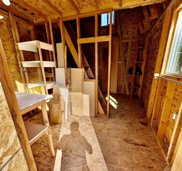 Wood-finish flooring throughout an unfinished interior with exposed wood framing