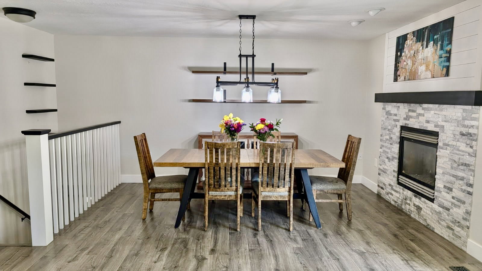 Open-concept dining area featuring wood-finish flooring and a stone-clad fireplace