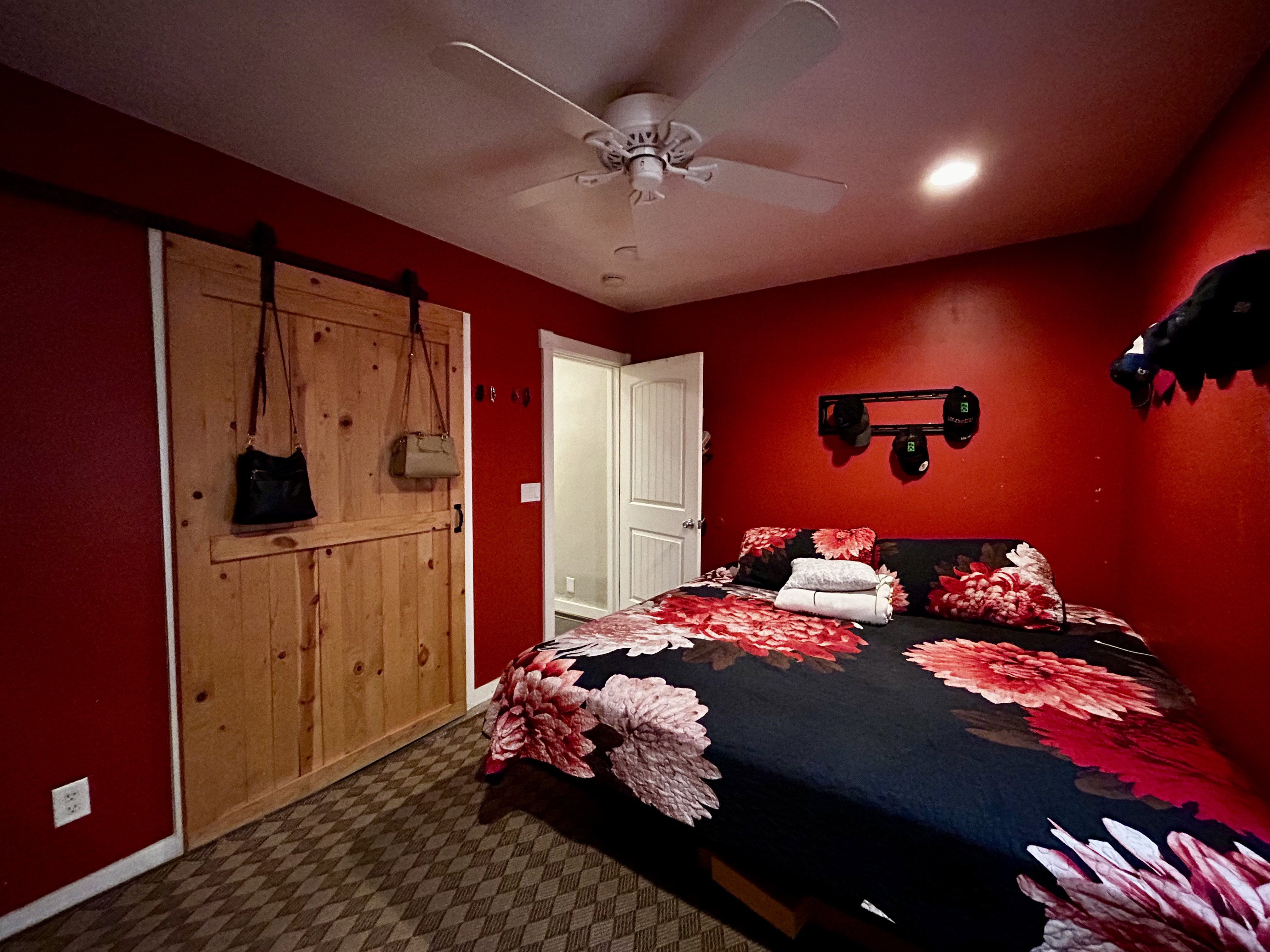 Bedroom #1 featuring a natural wood-finish barn door with black hardware, and a ceiling fan with integrated lighting