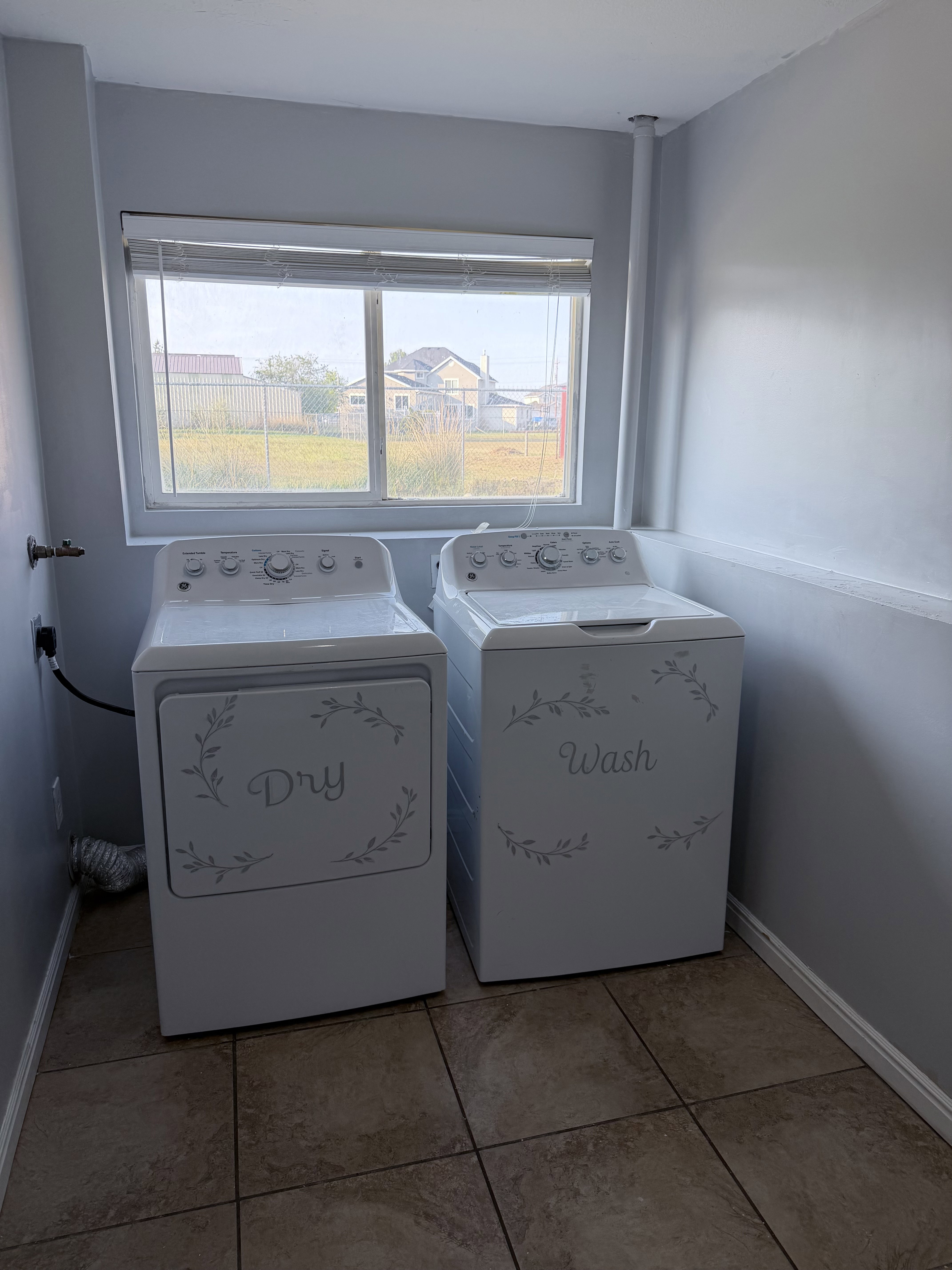 Utility space featuring a window with blinds, tile flooring, and light gray walls