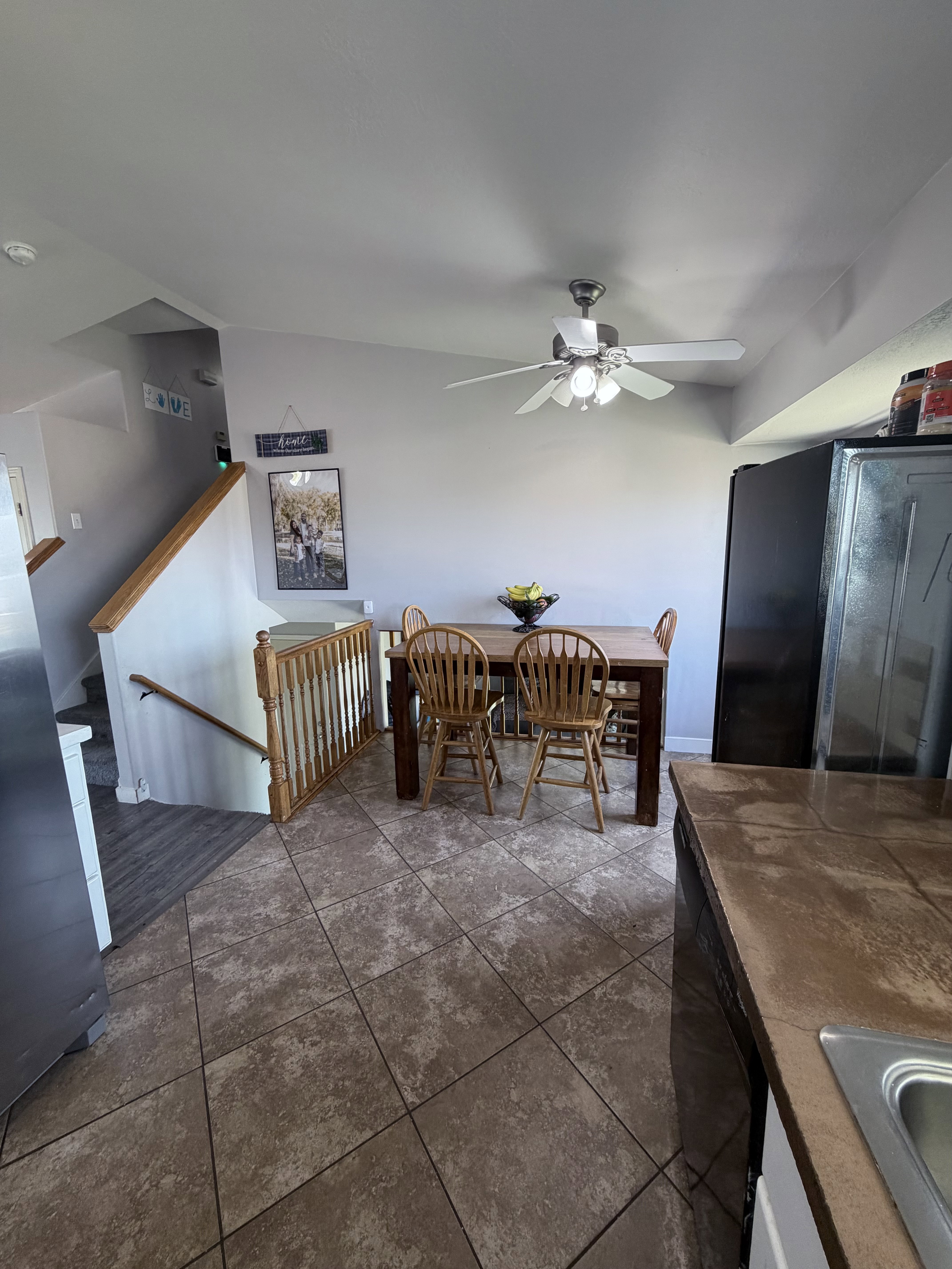 Dining area featuring a ceiling fan with light fixture, tile flooring, and stairs