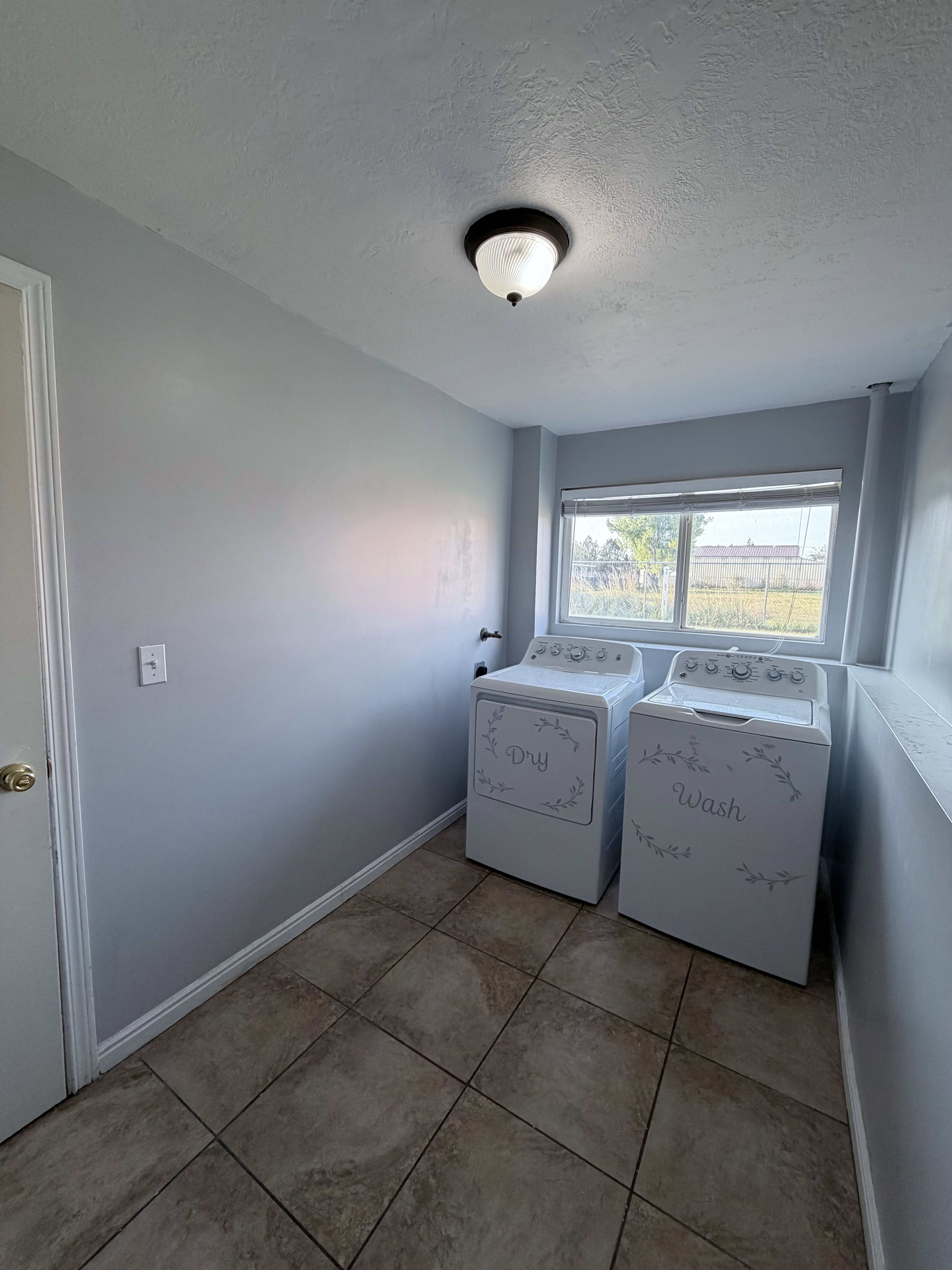 Utility area featuring tiled flooring, a window, and a flush mount light fixture