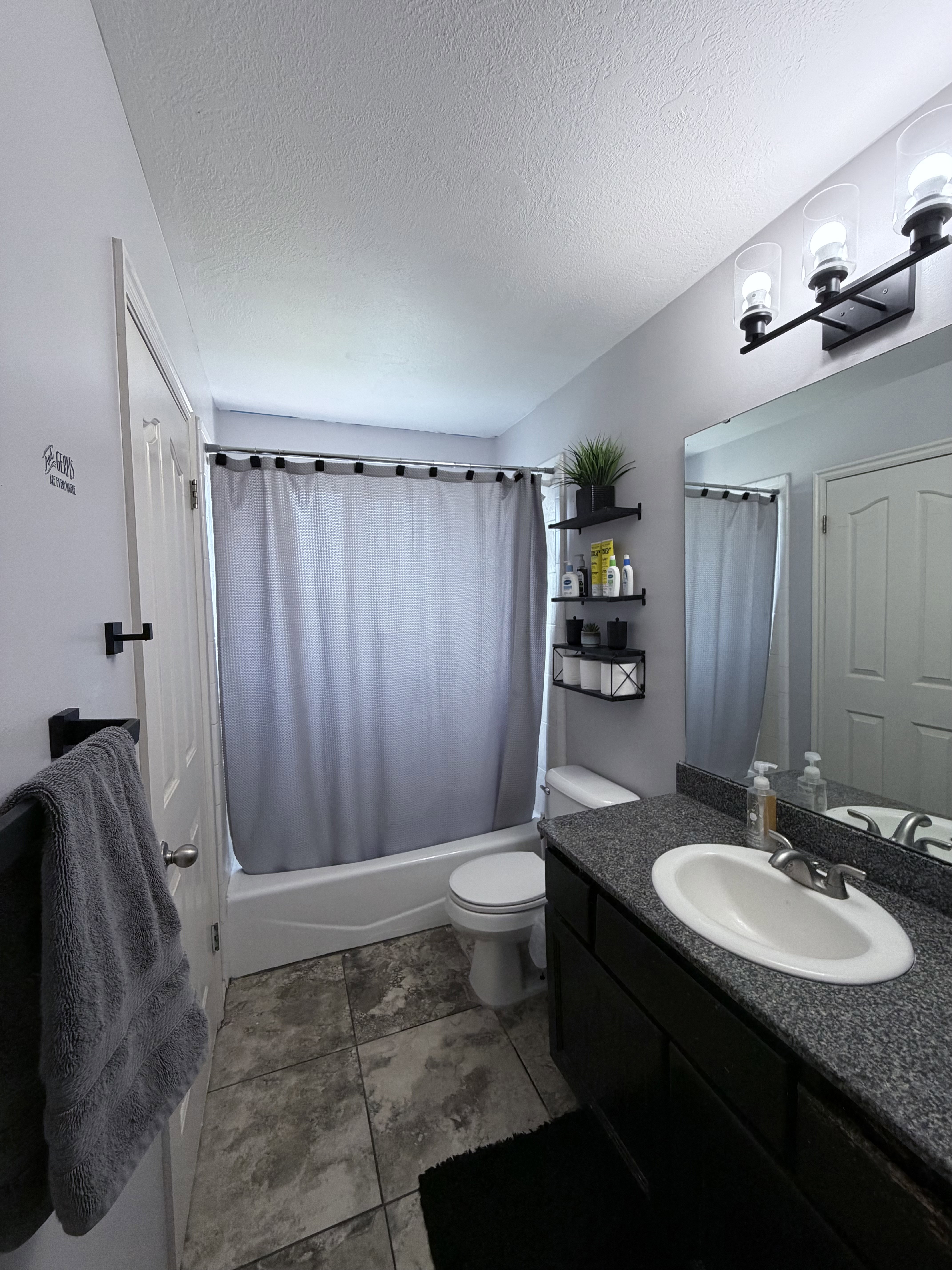 Contemporary bathroom featuring a dark wood-finish vanity with a speckled countertop and an integrated sink