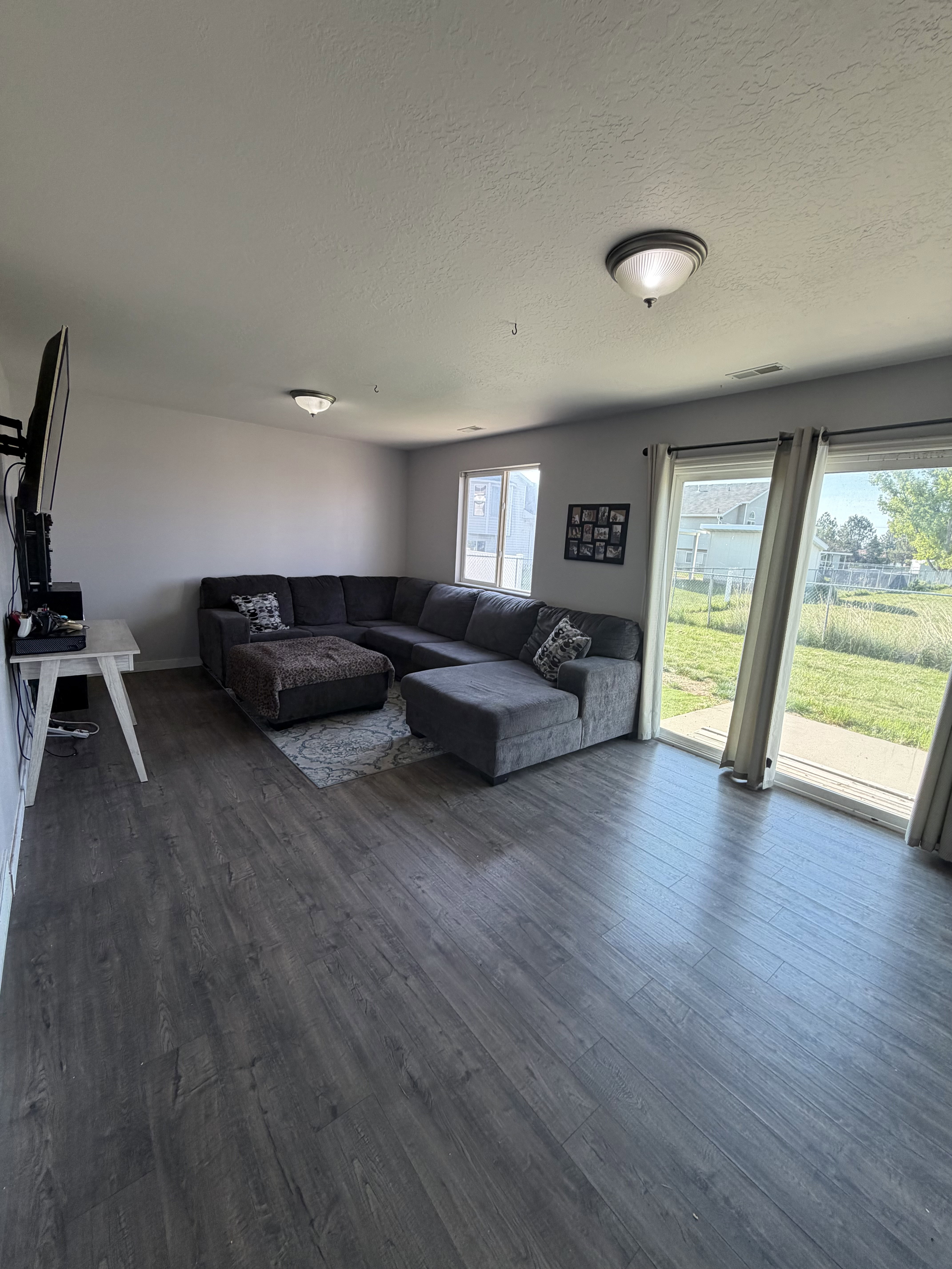 Spacious living area featuring wood-finish flooring and multiple windows