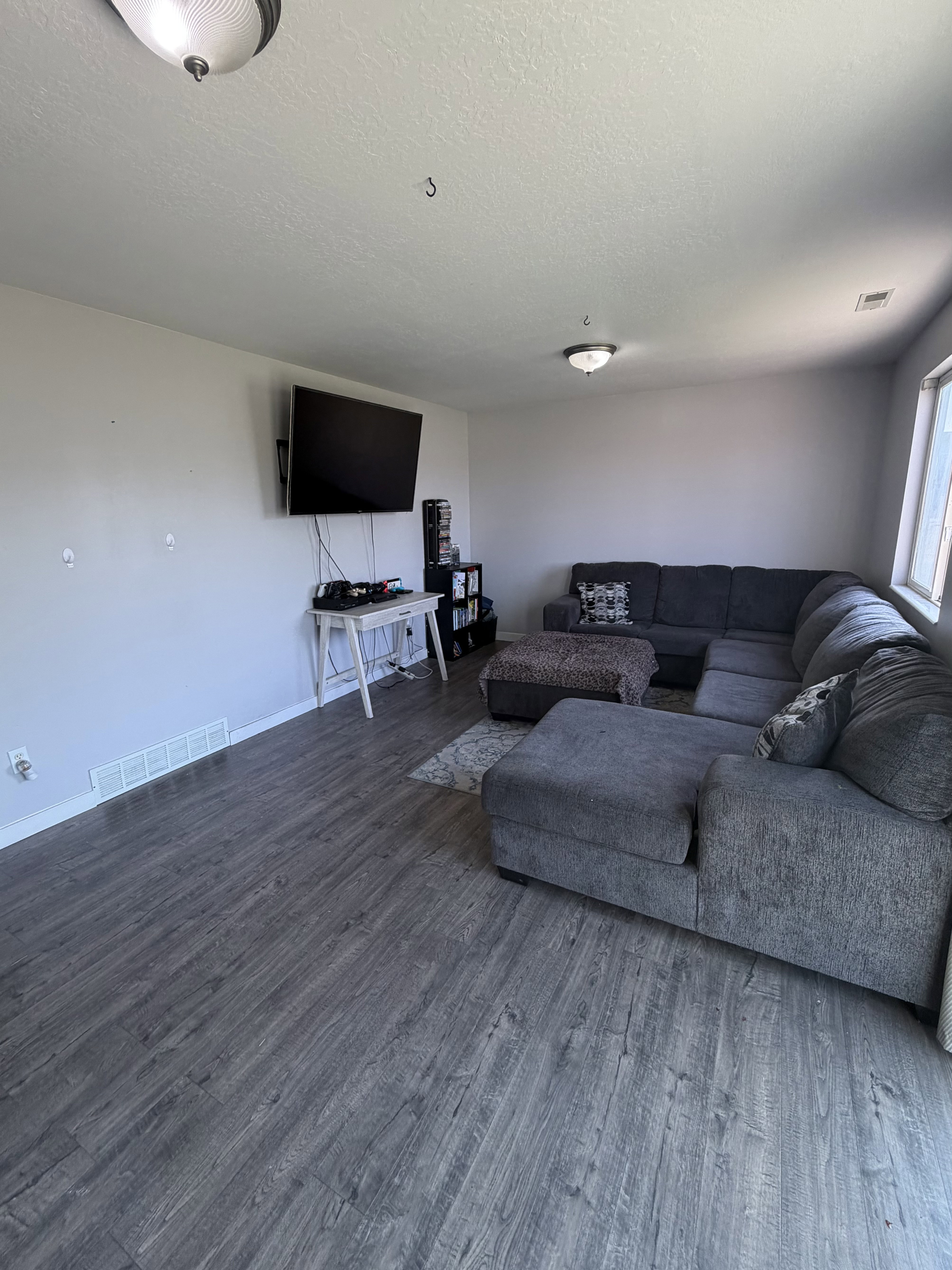Spacious living area featuring wood-finish flooring, light neutral wall tones, and recessed lighting