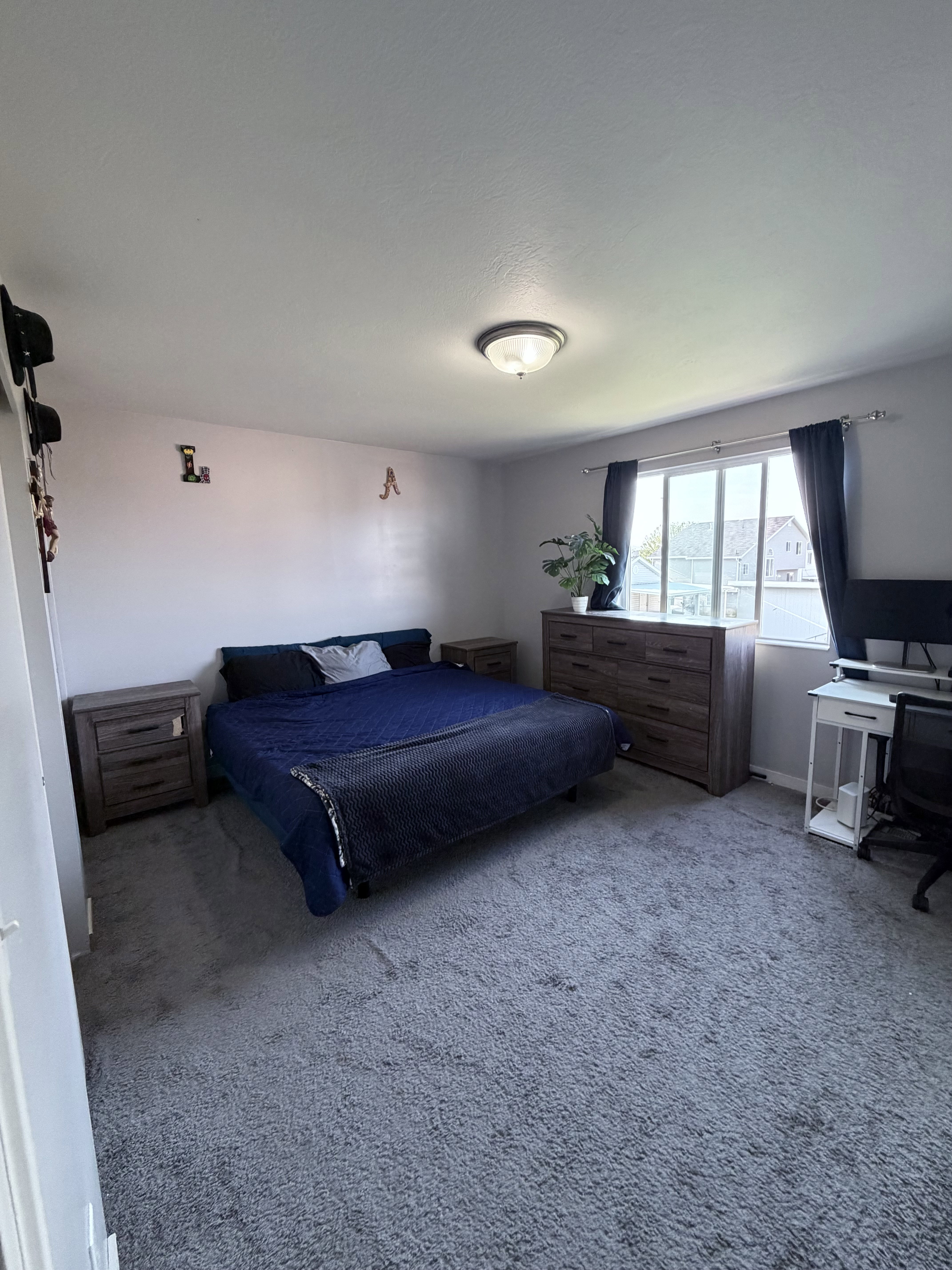 Carpeted room featuring a ceiling-mounted light fixture, a window with dark curtains, and light-toned walls
