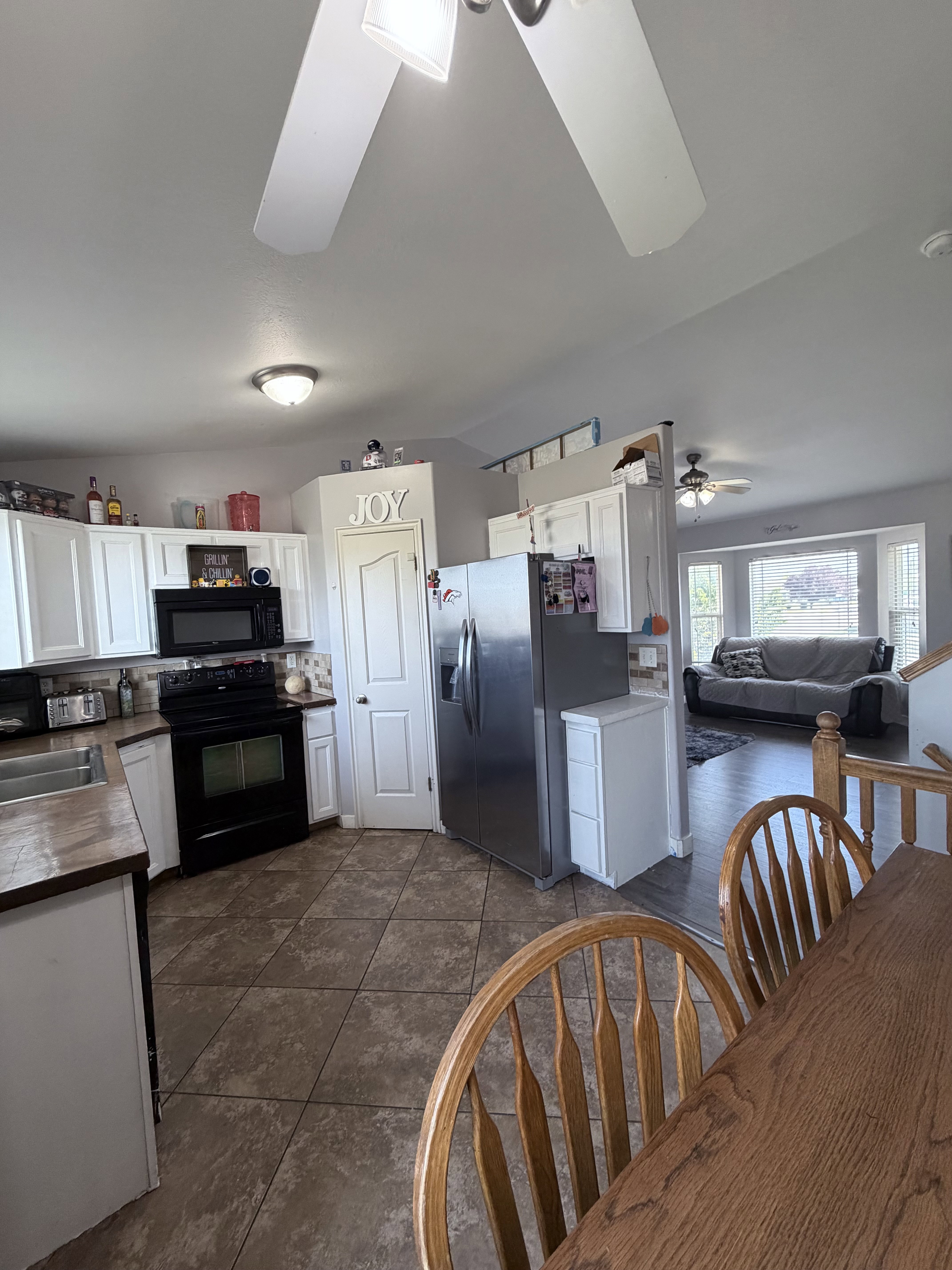 Open-concept kitchen featuring white cabinetry, tile flooring, and wood-finish countertops