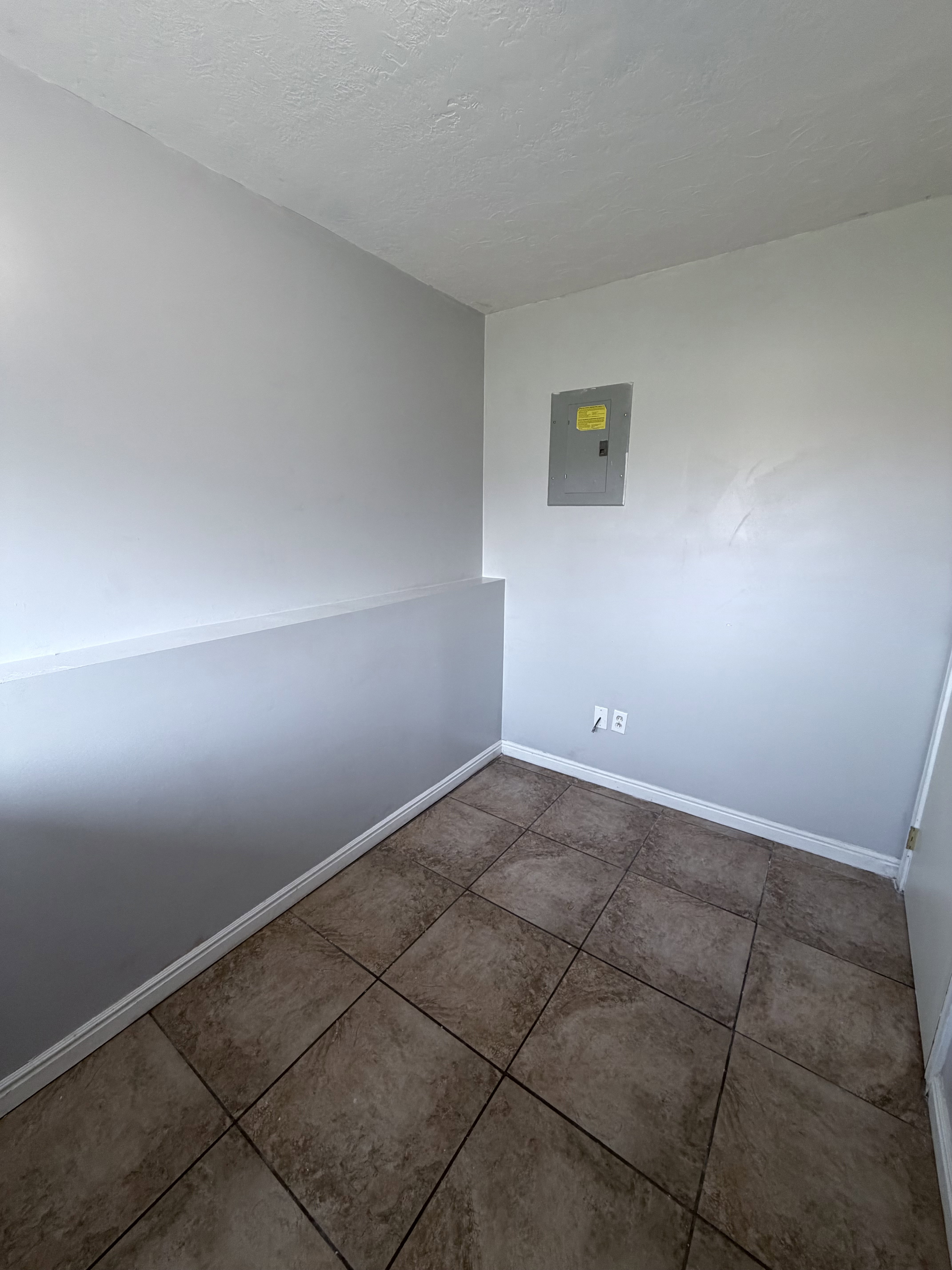 Neutral-toned tiled flooring complemented by light gray walls and white baseboards