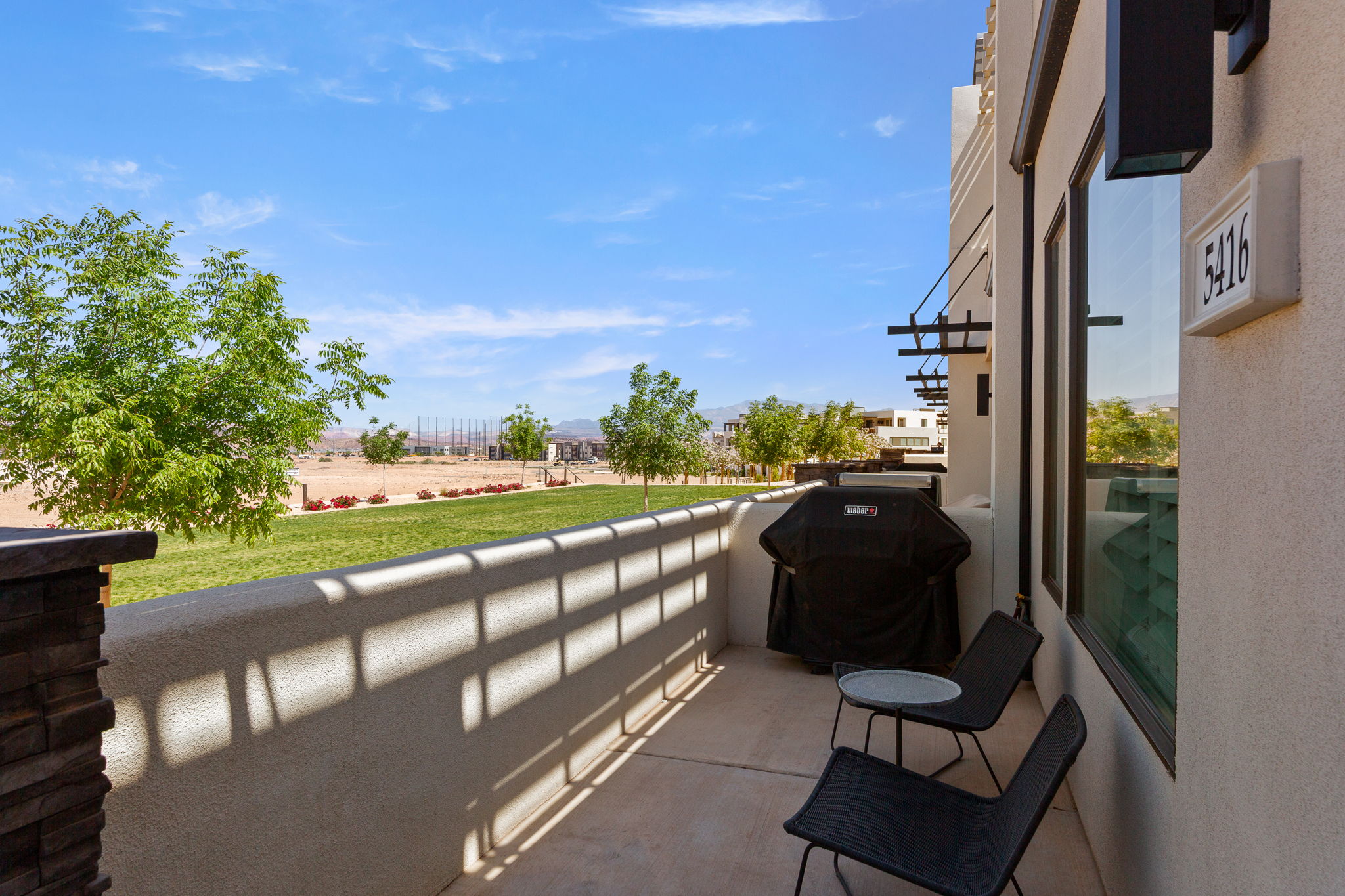 Private patio featuring a stucco railing, concrete flooring, and a stacked stone pillar