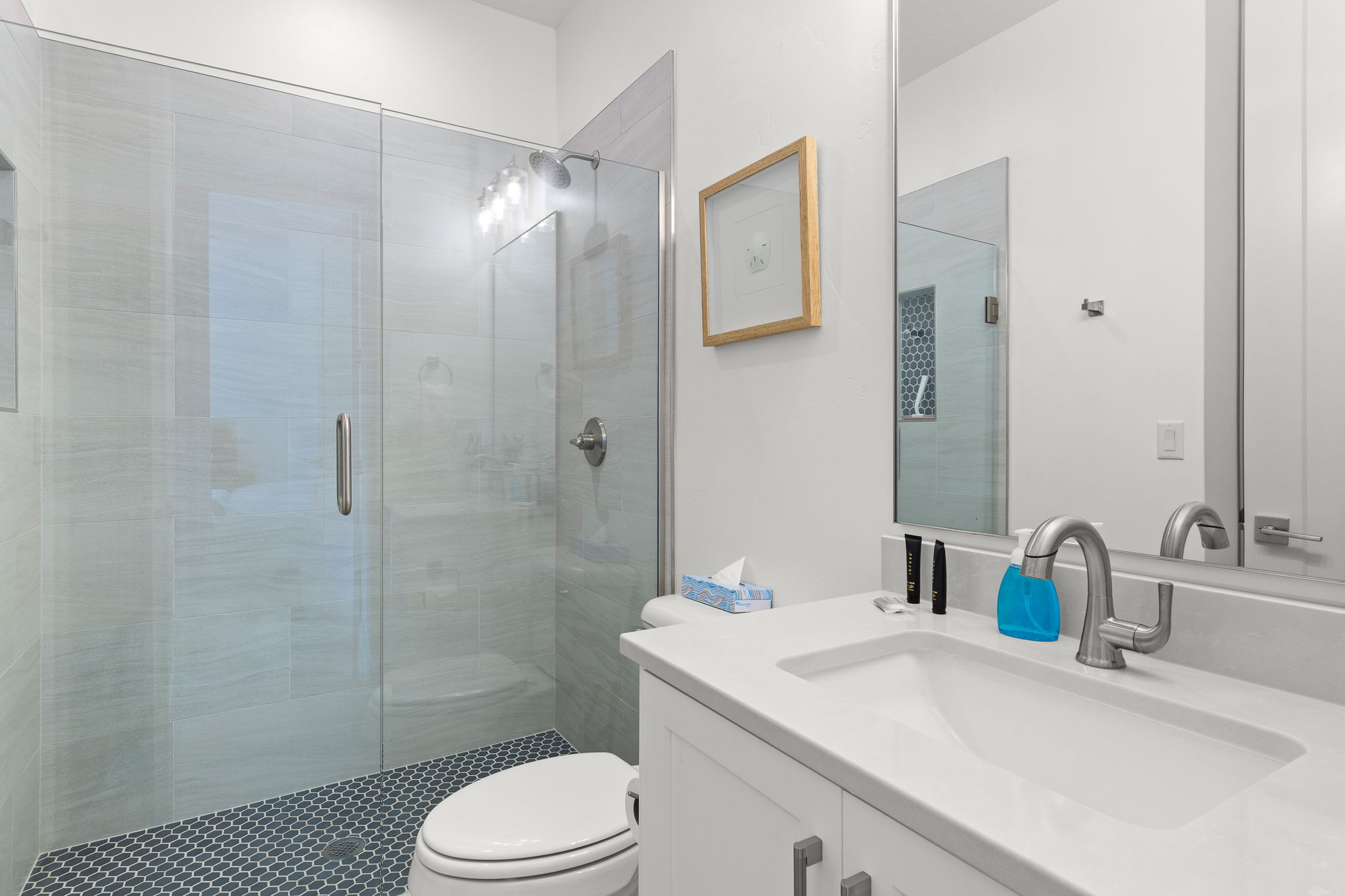Bathroom featuring a walk-in shower with glass enclosure, light gray wall tile, and dark penny tile flooring