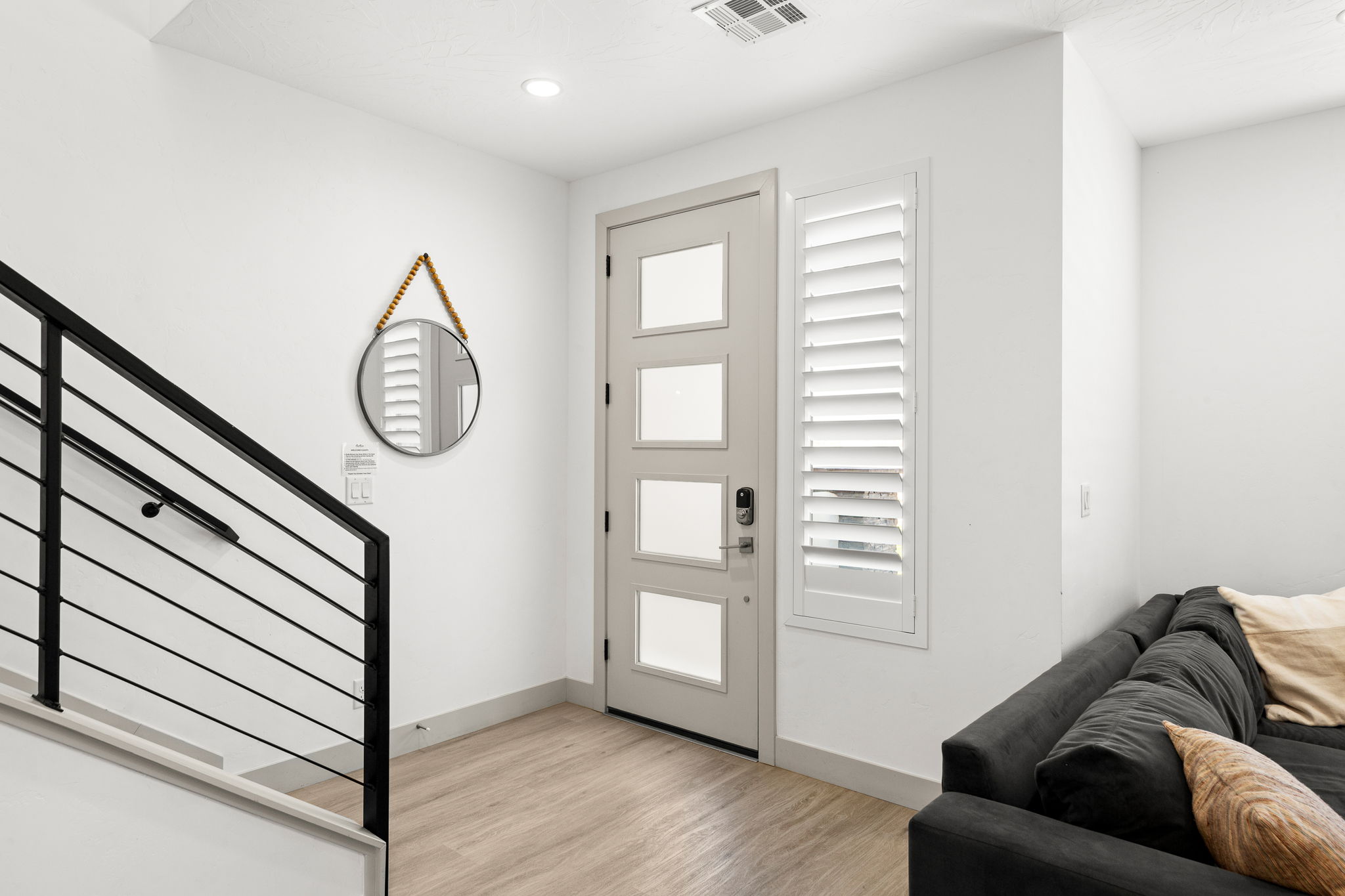 Entryway featuring a modern light-colored door with frosted glass panels, plantation shutters, recessed lighting, and wood-finish flooring