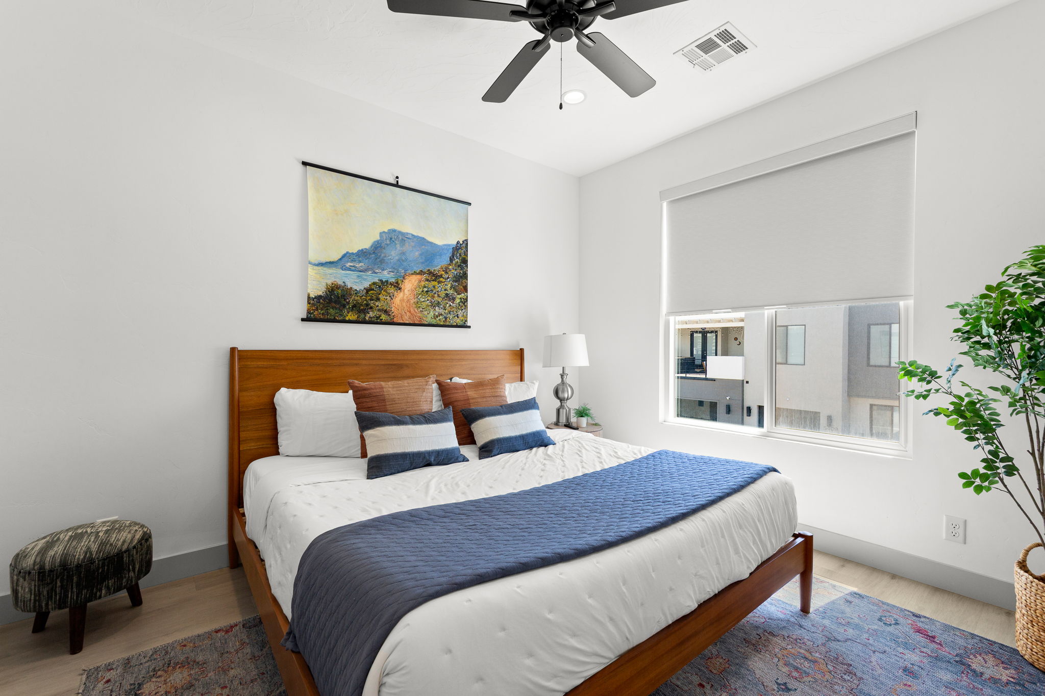Bright room featuring a ceiling fan, light wood-finish flooring, and a large window with a roller shade