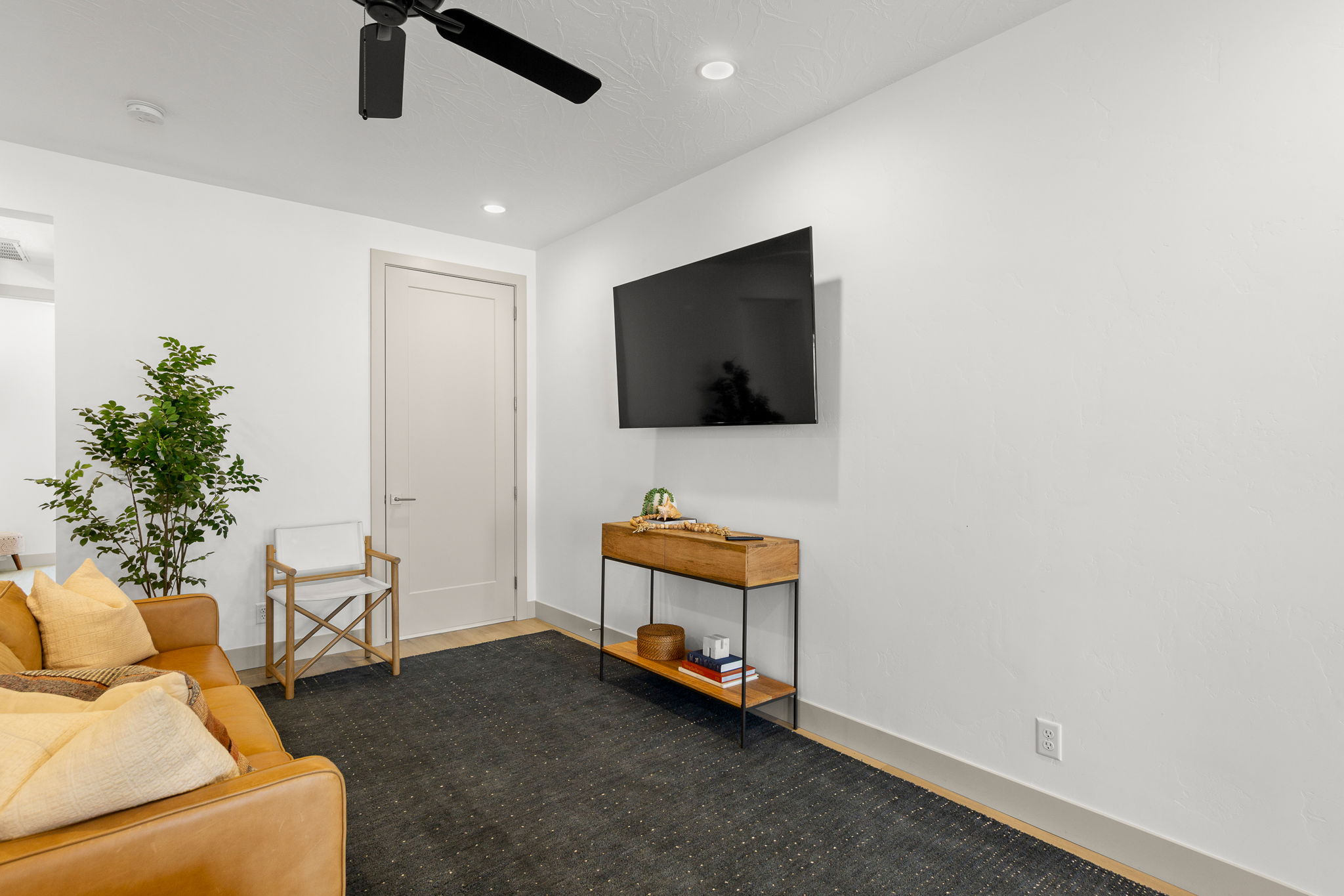 Spacious living area featuring light wood-finish flooring and a contemporary overhead fan