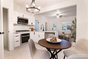 Modern kitchen featuring white cabinetry, stainless steel appliances, and light-tone wood-finish flooring
