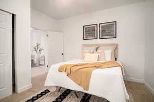 Plush carpeted room featuring bright white walls, a built-in closet with bifold doors, and a paneled door entry