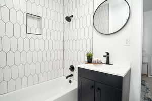 Modern bathroom featuring a white bathtub with black fixtures, an integrated shower niche, and elongated hexagonal wall tiling