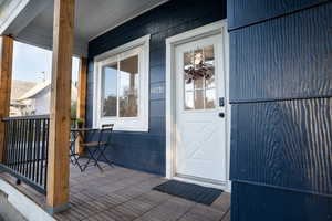 Covered front porch featuring wood-finish flooring, natural wood posts, and black metal railings