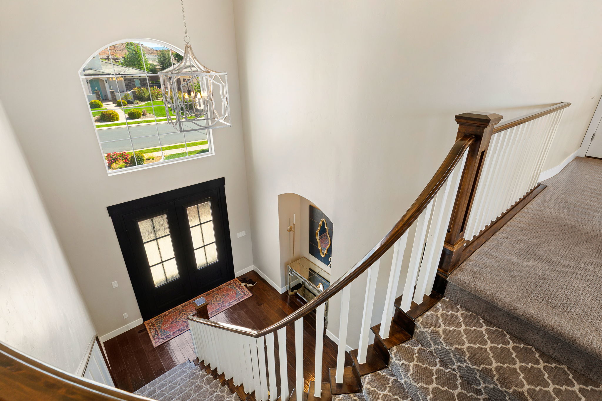 Two-story entryway featuring a dark wood-finish double entry door with frosted glass panes
