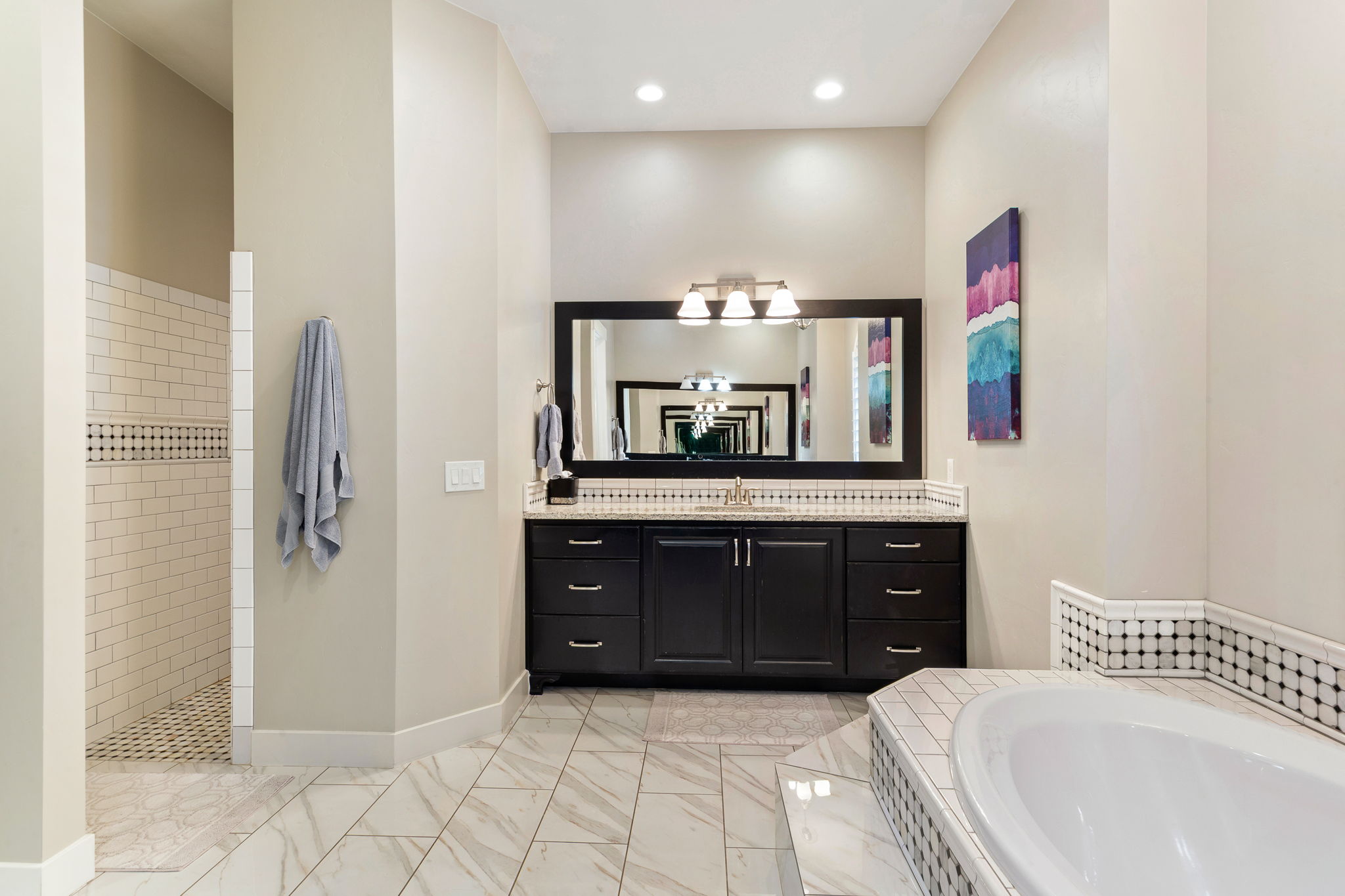 Spacious bathroom featuring a dark wood vanity with a light-colored countertop, an undermount sink, and an expansive framed mirror