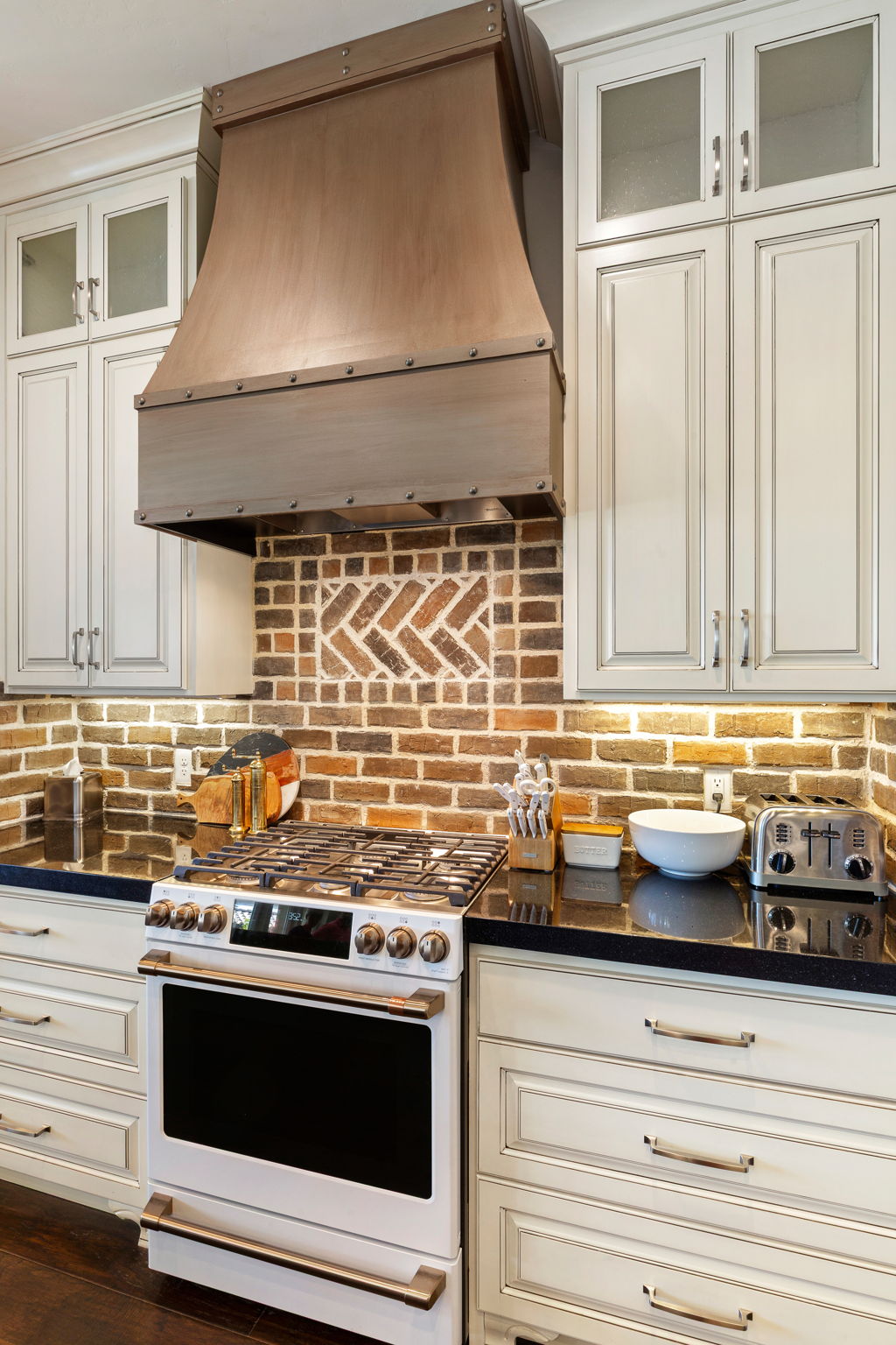 Custom metal range hood above a gas range with an integrated oven
