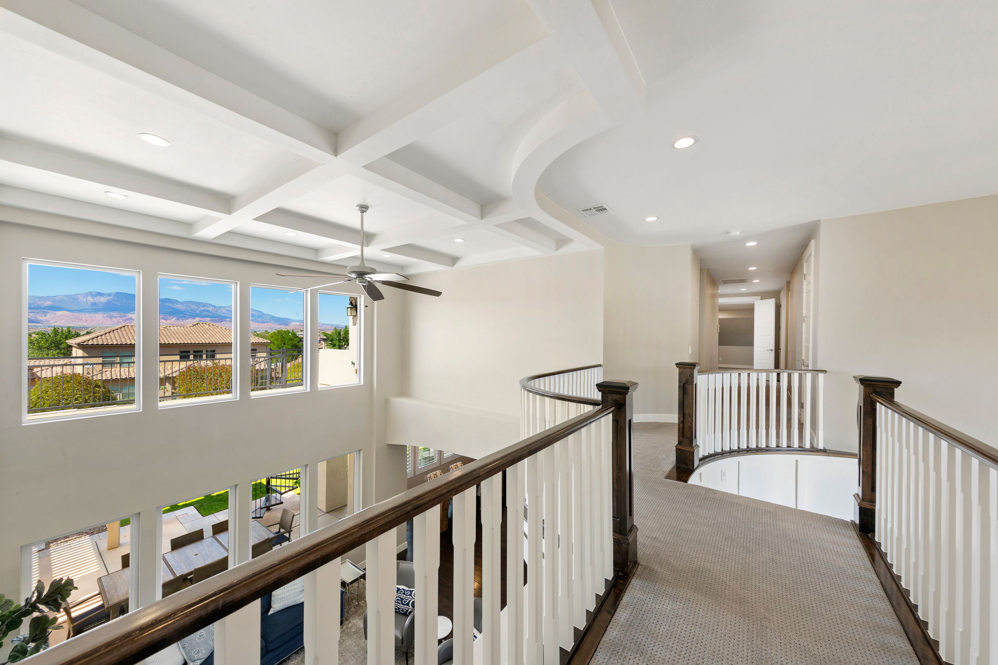 Upper-level hallway featuring a curved railing with dark wood and white balusters