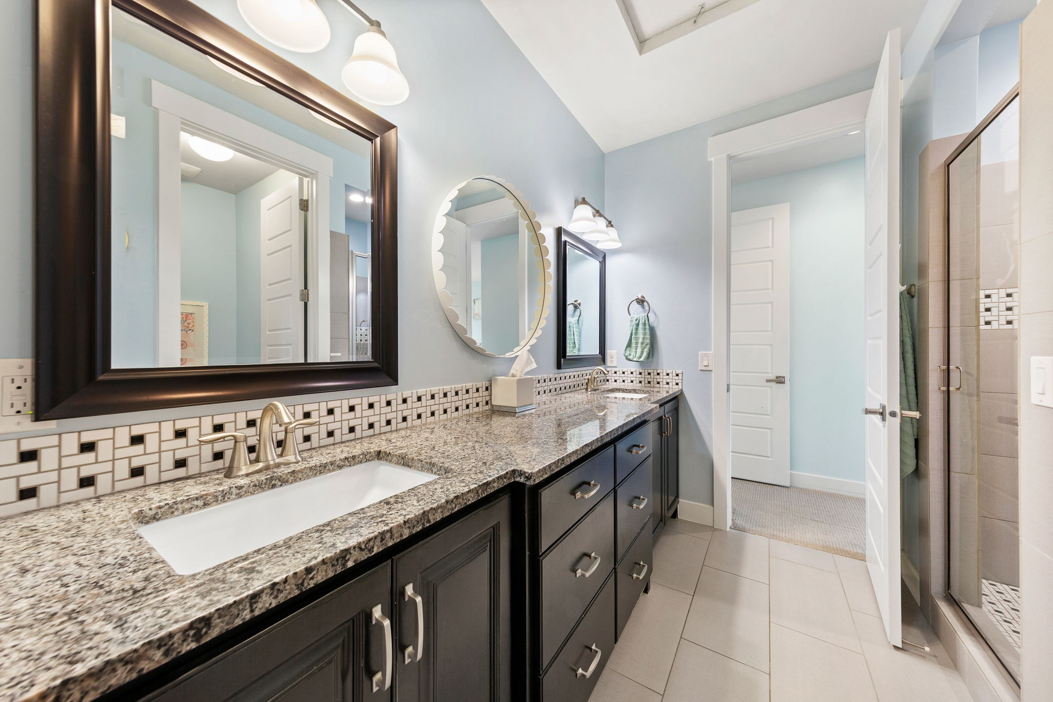 Double vanity featuring granite countertops, undermount sinks, and dark wood-finish cabinetry