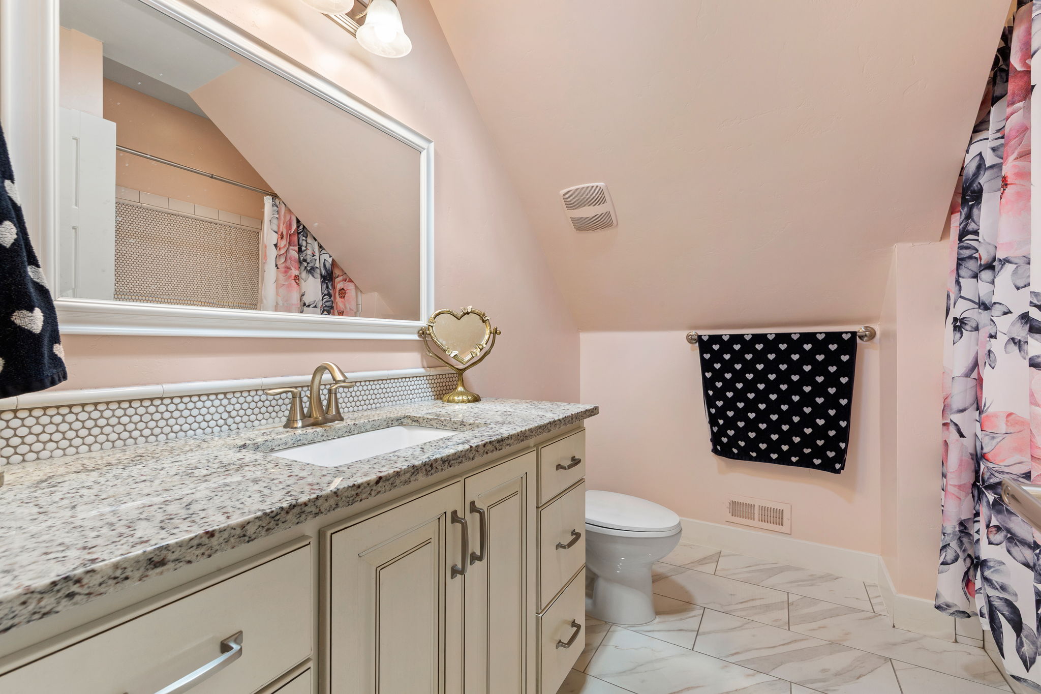 Bathroom featuring a single vanity with an integrated sink, granite countertop, and white hexagonal tile backsplash