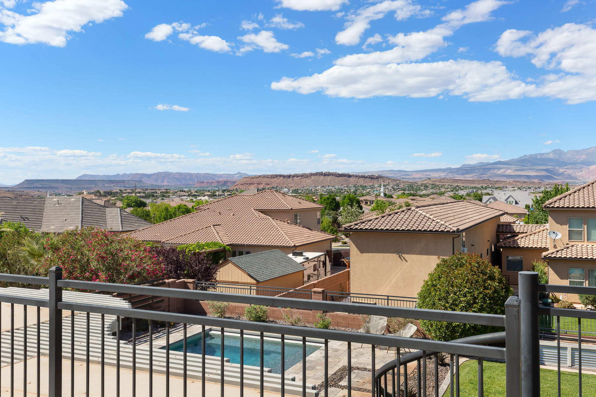 Outdoor living area featuring a swimming pool, a black metal railing, and a pergola-covered patio