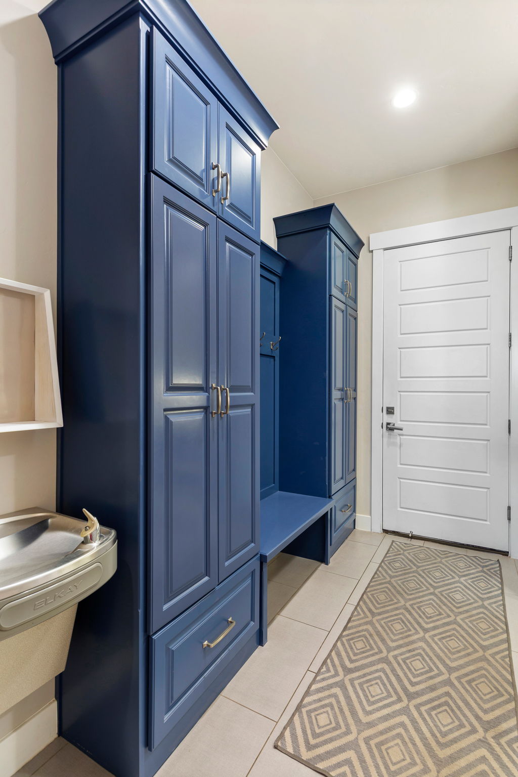 Built-in storage cabinetry in a deep blue finish, featuring shaker-style doors and drawers with brushed nickel hardware