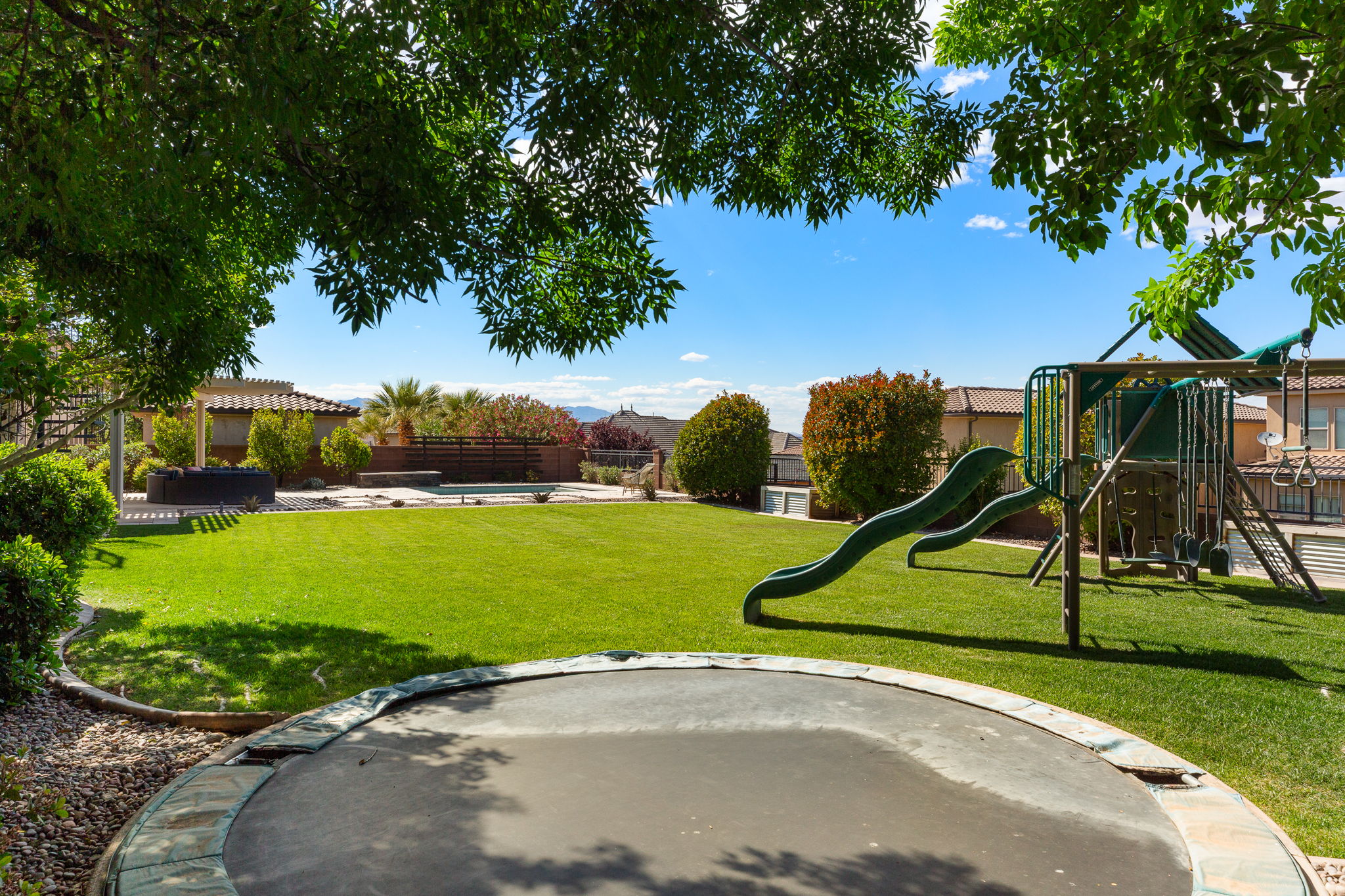 Expansive backyard featuring a manicured lawn, established landscaping, and perimeter fencing