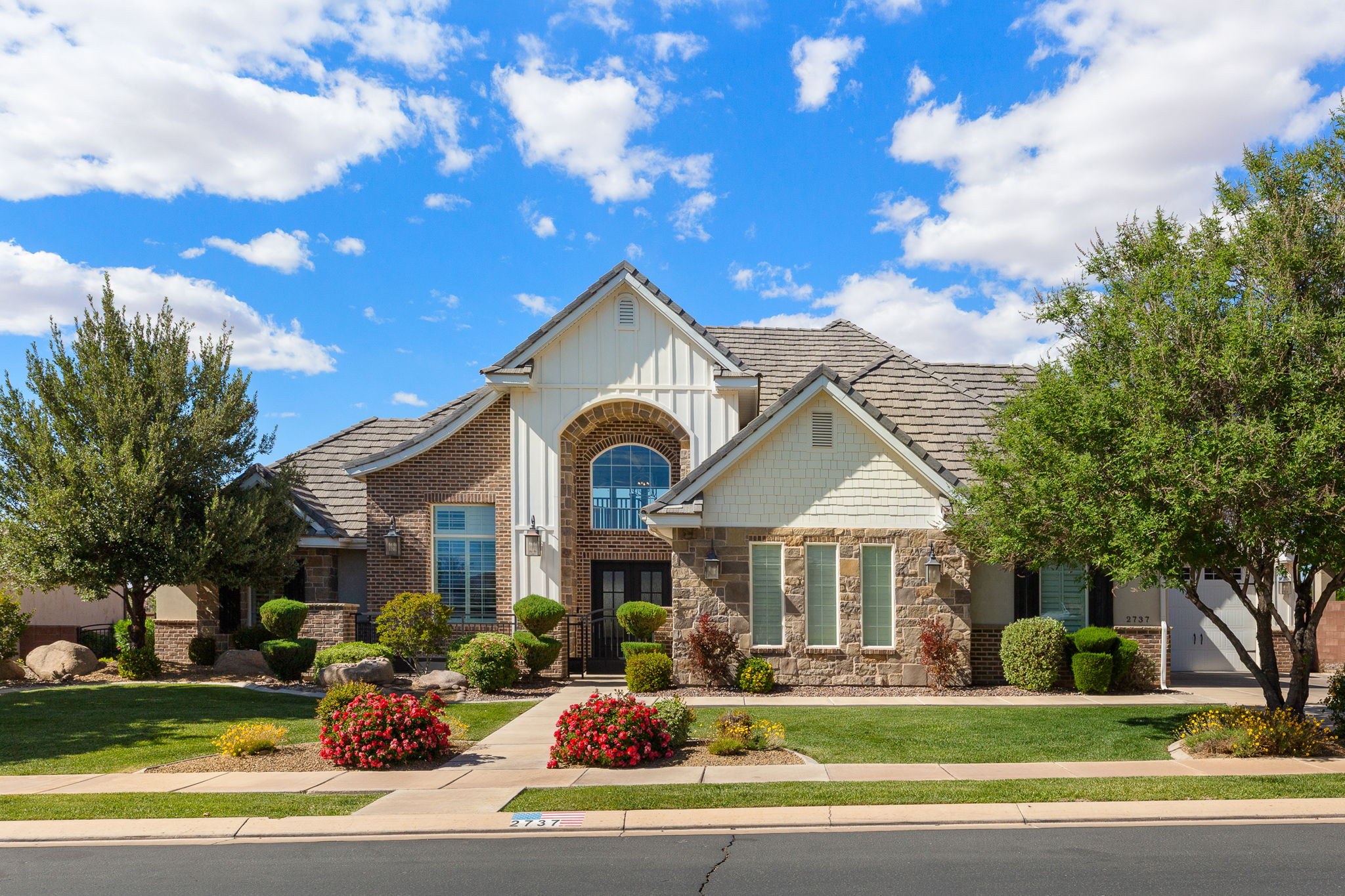 Stately exterior with a brick and stone facade, featuring a prominent arched window and a covered entry