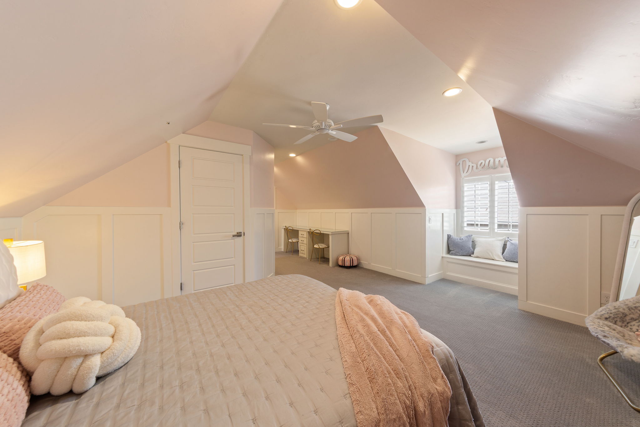 Spacious room featuring sloped ceilings, white paneled wainscoting, and recessed lighting
