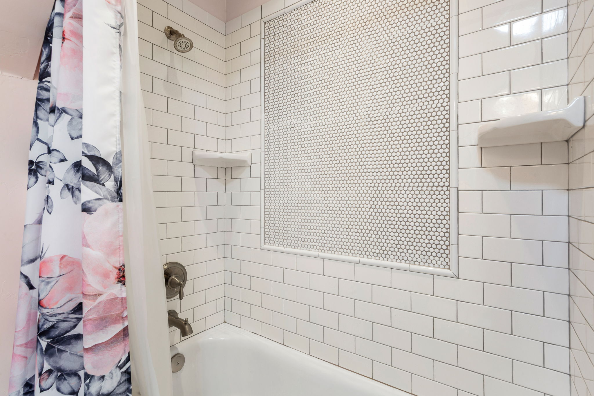 Bathtub with white subway tile surround, penny tile accent niche, and brushed nickel fixtures
