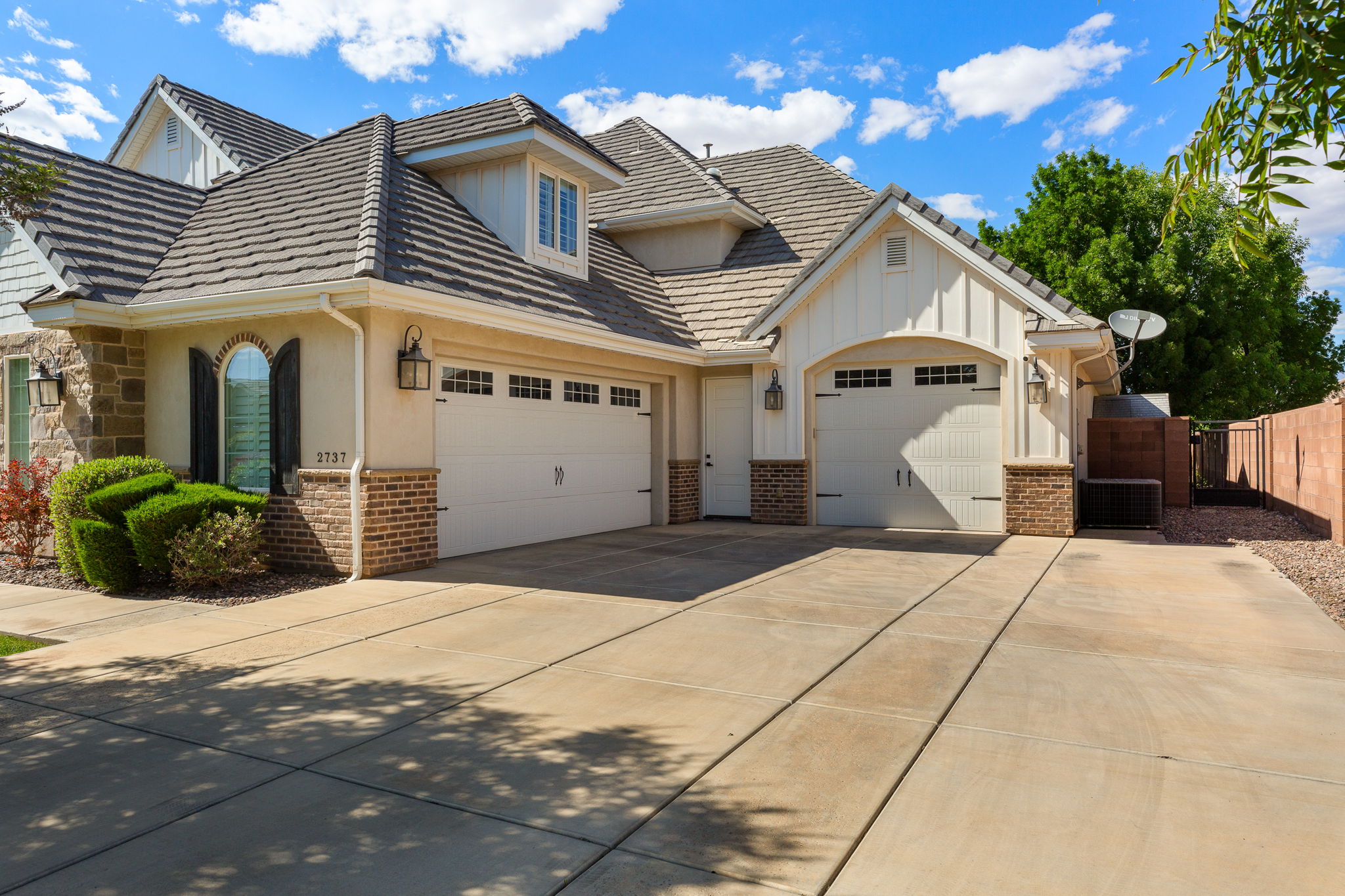 Stucco and stone exterior with brick accents and a multi-car driveway