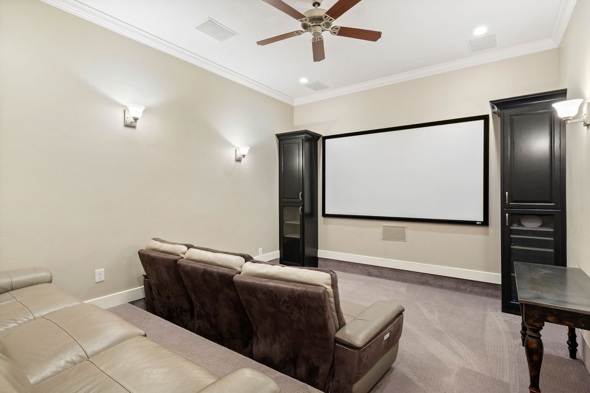 Dedicated media room featuring a large projection screen and built-in storage cabinetry