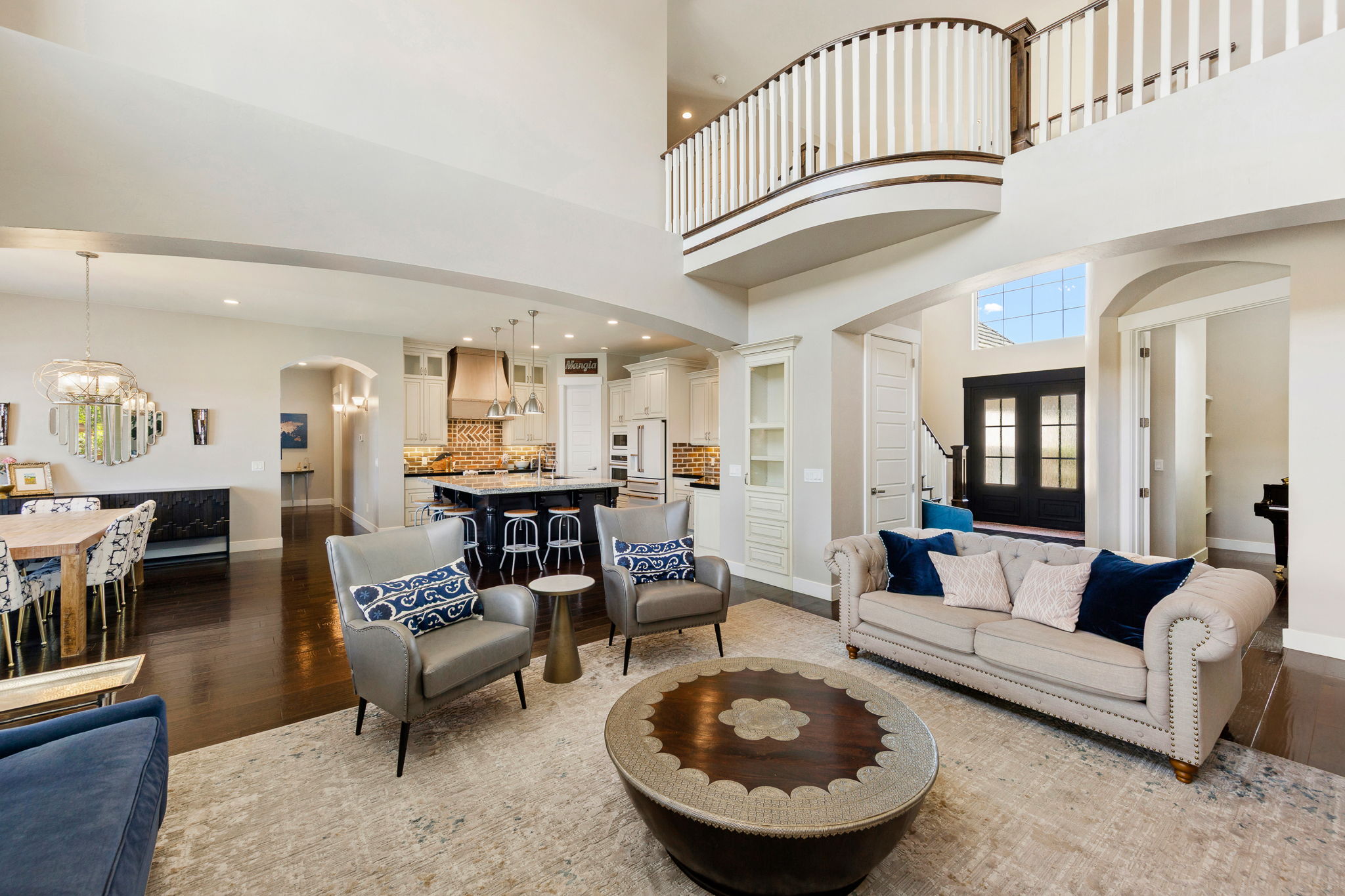 Open-concept living area with dark wood-finish flooring, a two-story ceiling, and an upper-level balcony
