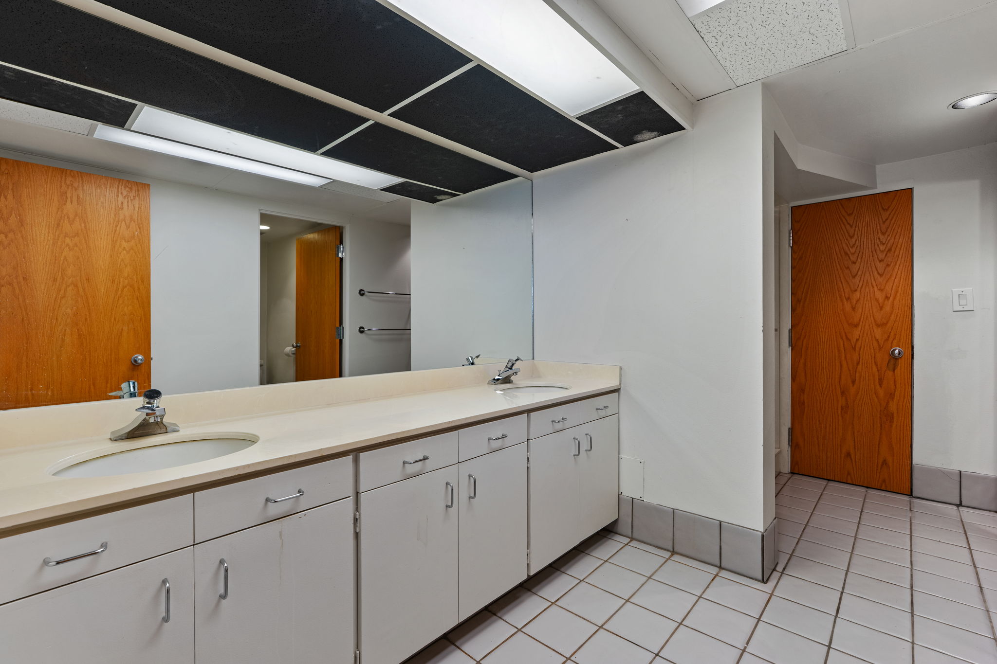 Long vanity featuring dual undermount sinks, chrome fixtures, and ample cabinet storage