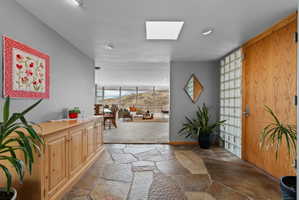Entryway featuring flagstone flooring, a natural wood entry door, and a glass block privacy wall